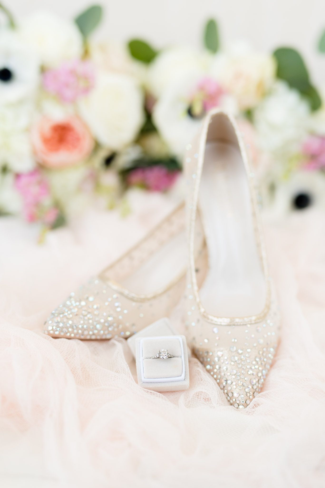 Bridal shoes and engagement ring sit on pink tulle