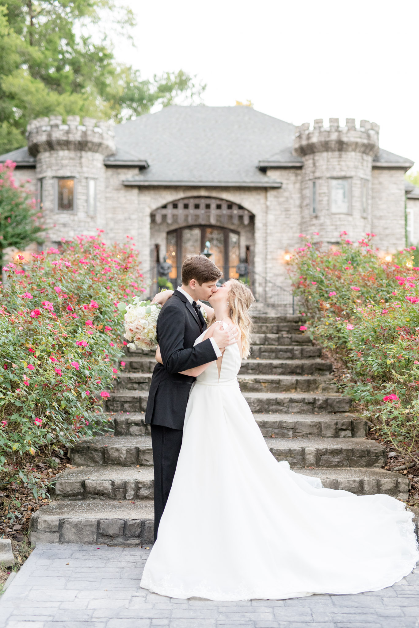 bride and groom kiss in front of castle.