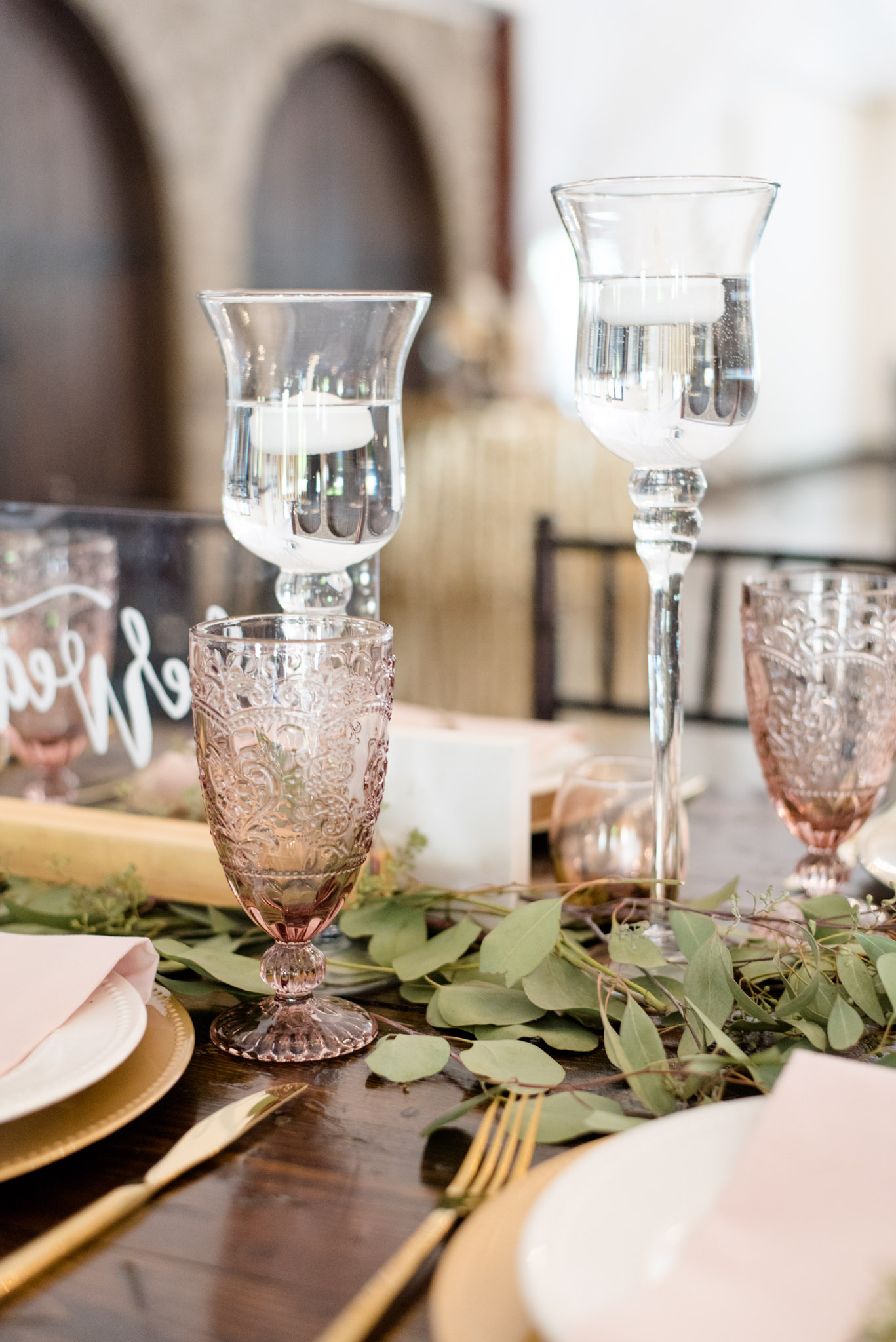 Pink drinking glasses and candles sit on table.