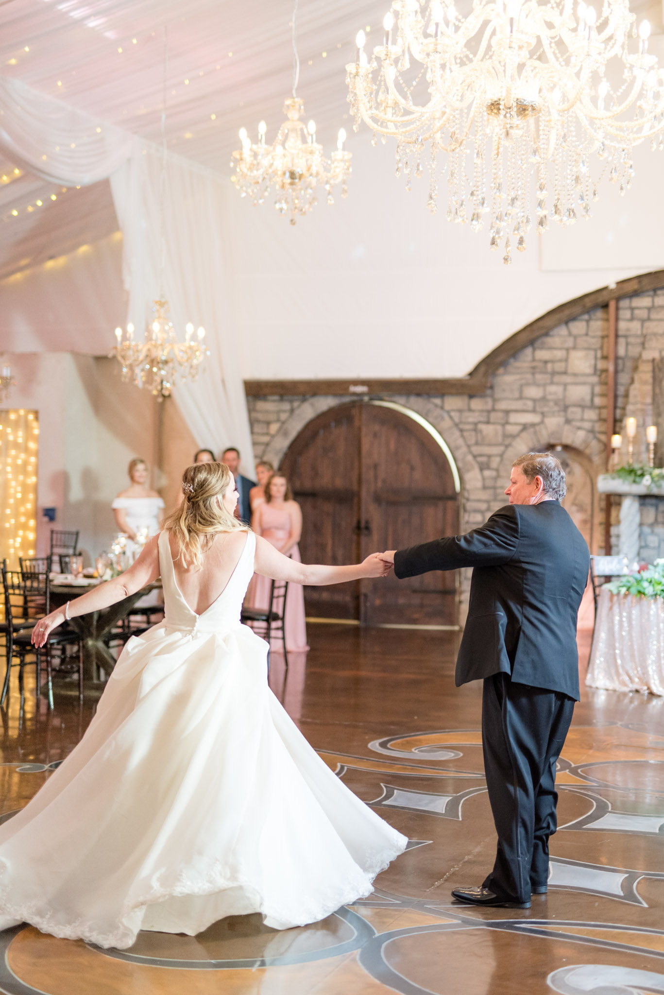 Father twirls bride during dance.