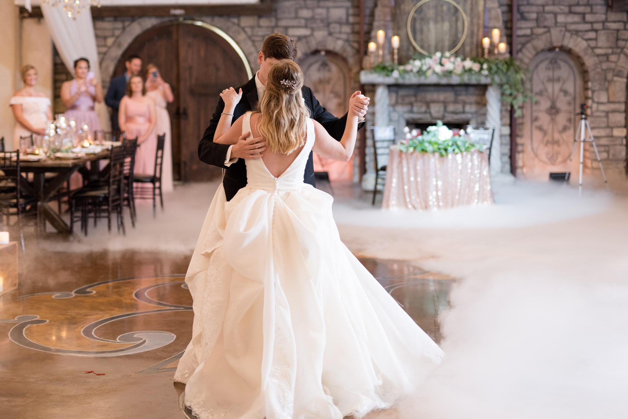 Bride and groom dance with fog on floor.