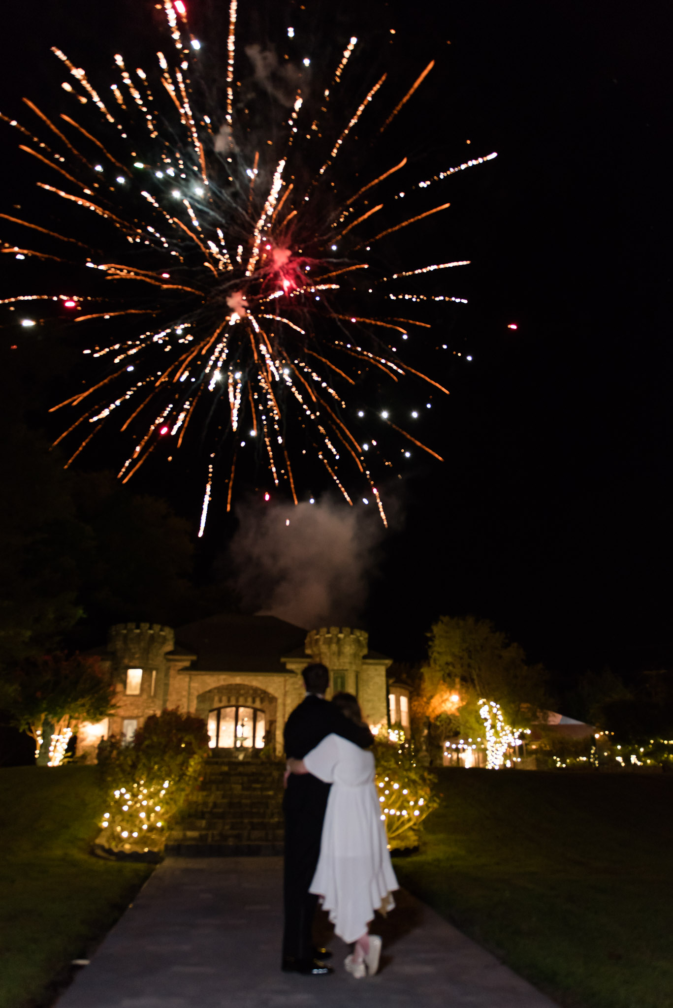 Bride and groom watch fireworks.