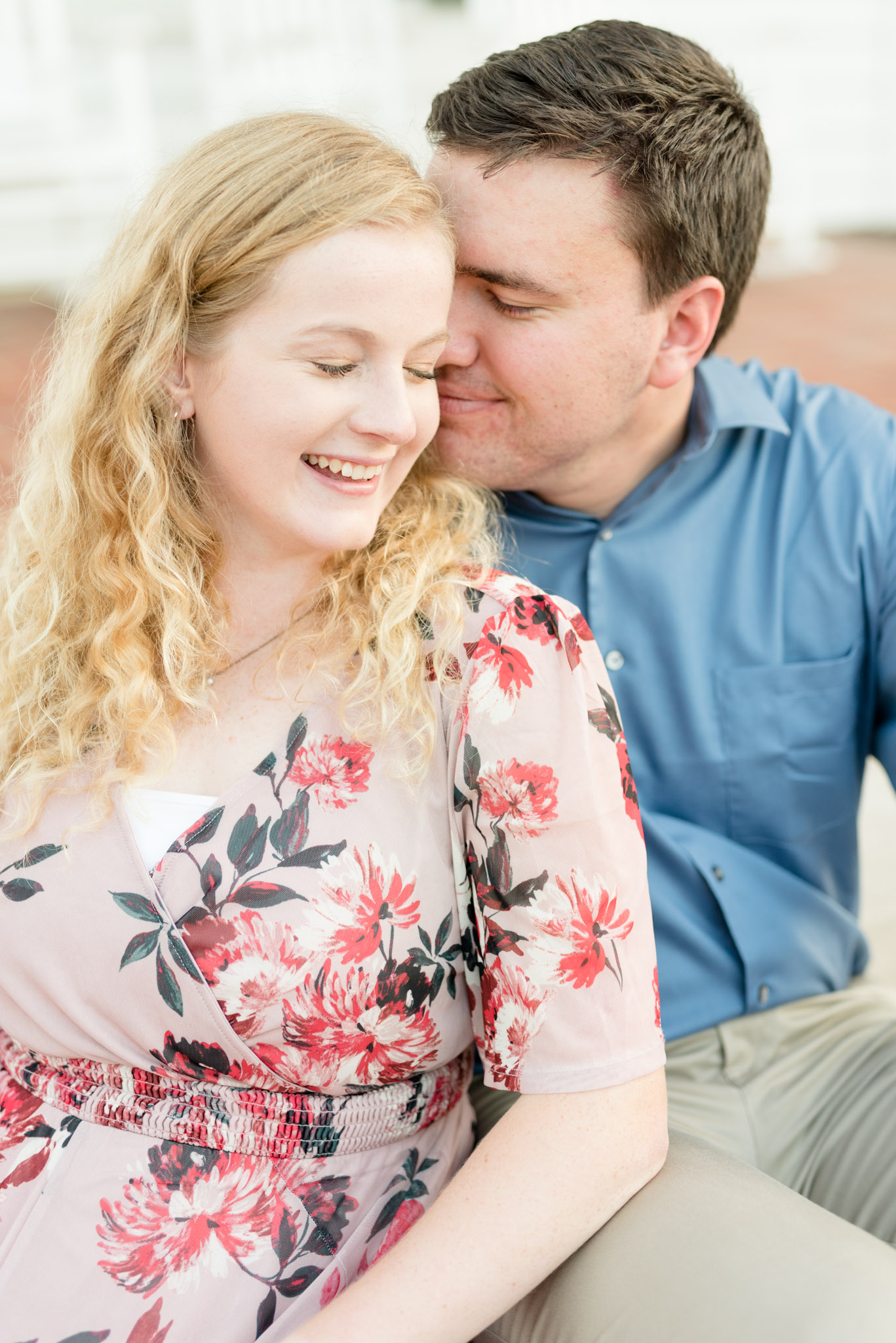 Couple snuggles while sitting on stairs.