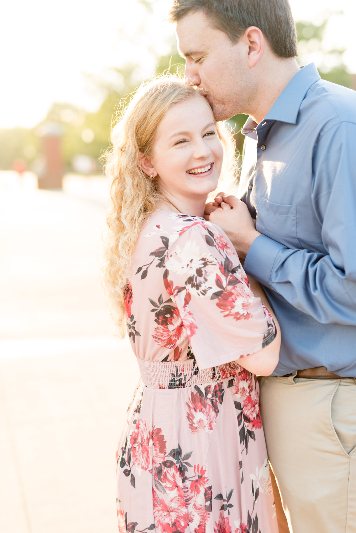 Woman laughs as fiance kisses her head.