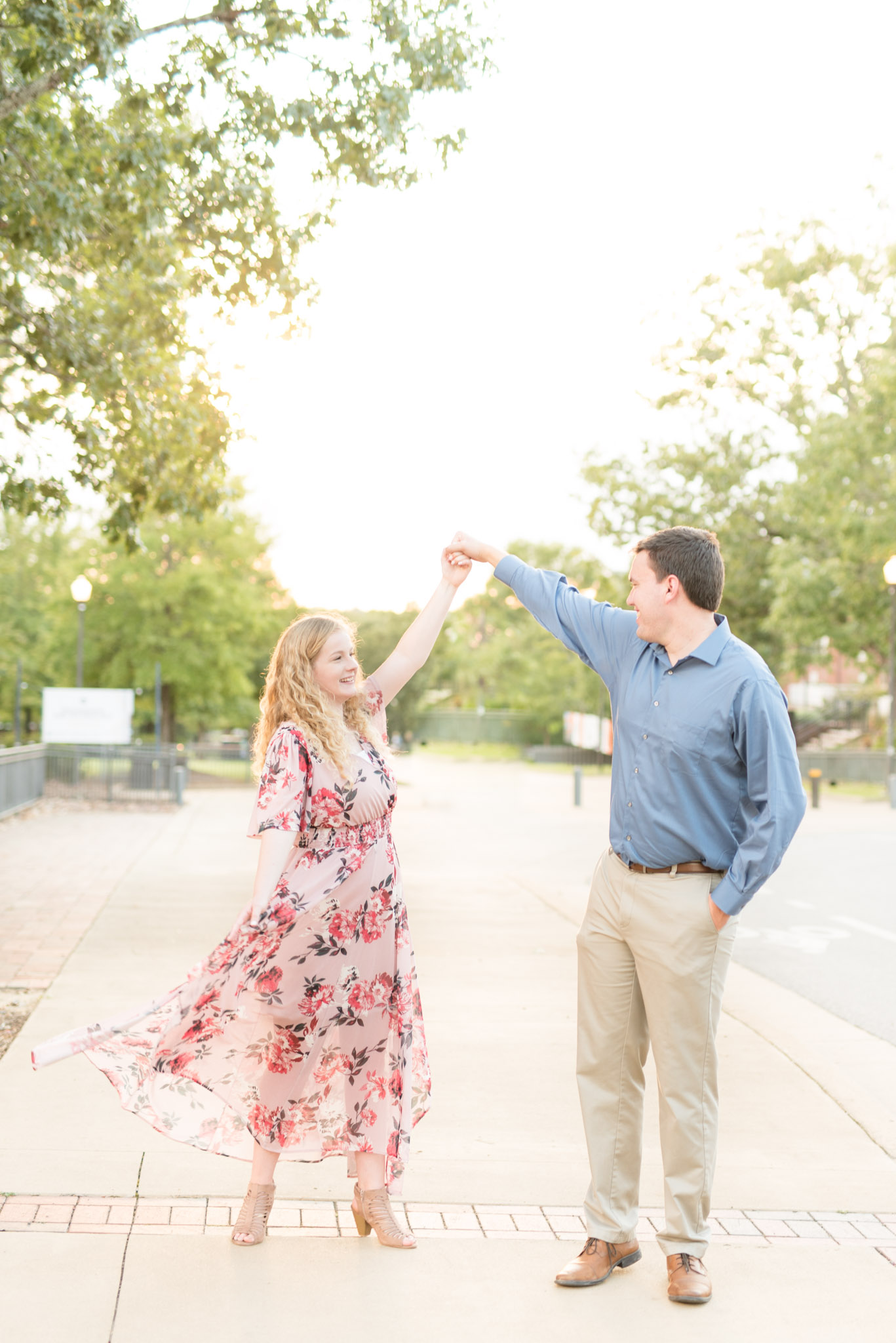 Man twirls bride-to-be at sunset.