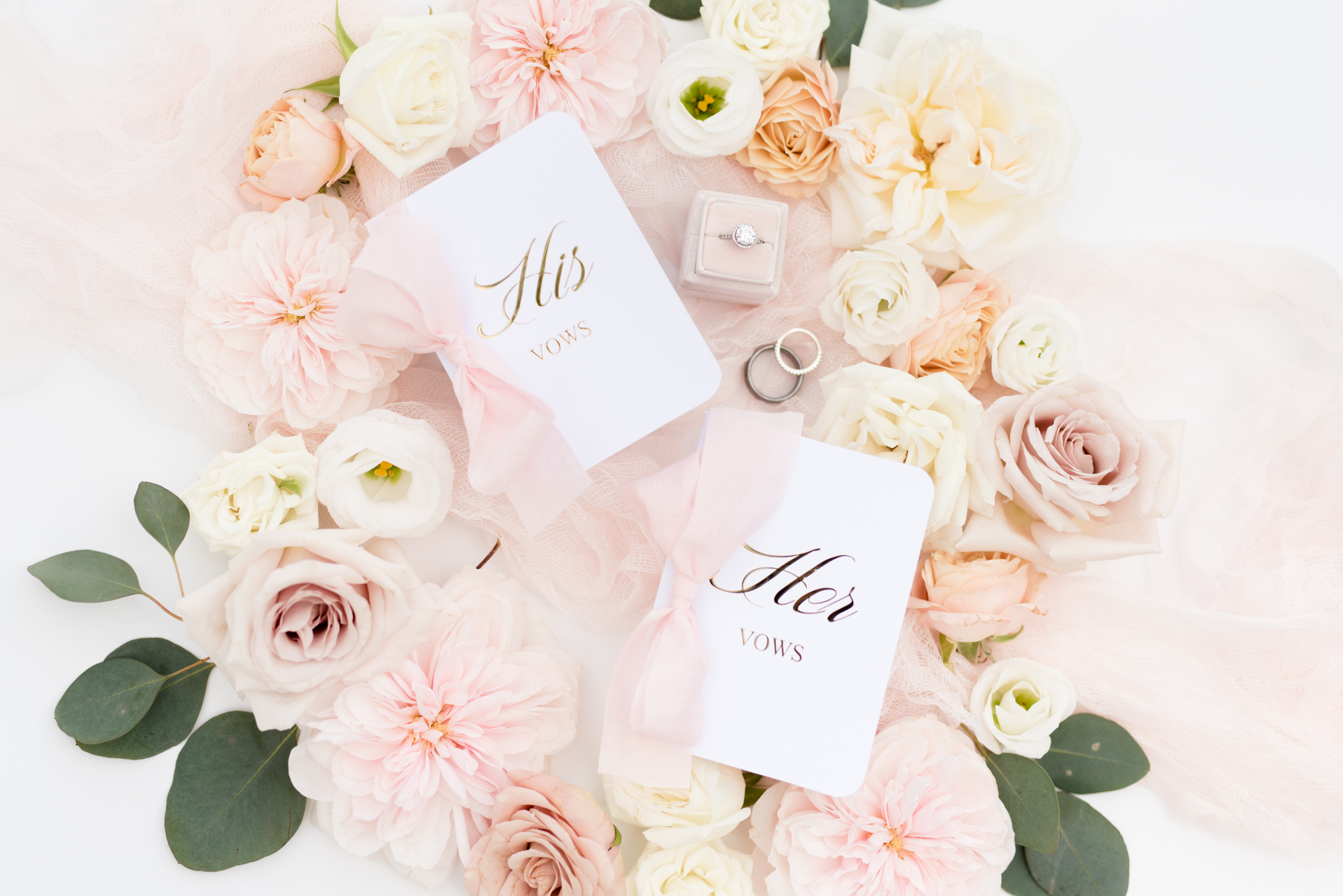 His and hers vow books sit with pink flowers.