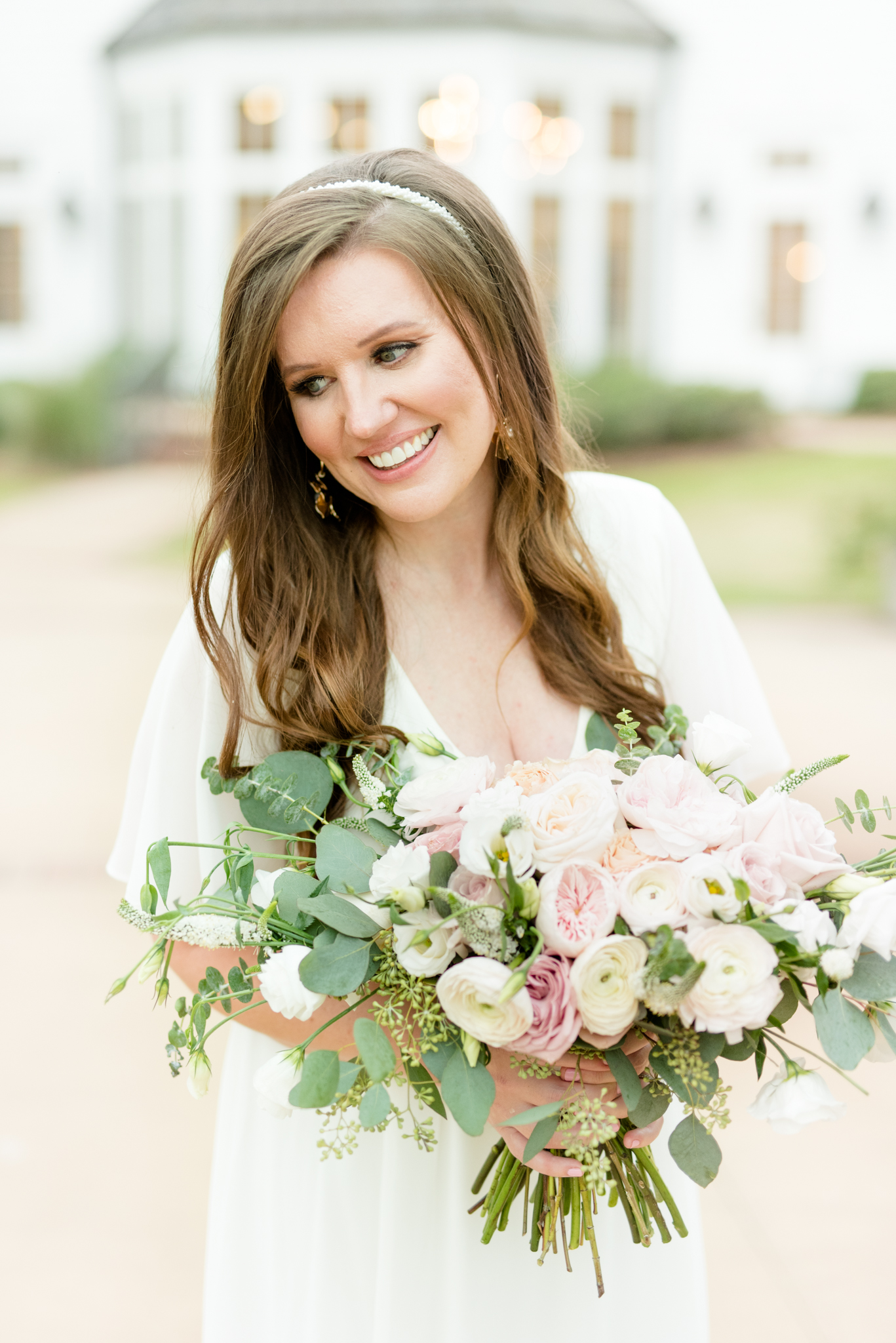 Bride smiles over shoulder while holding flowers.