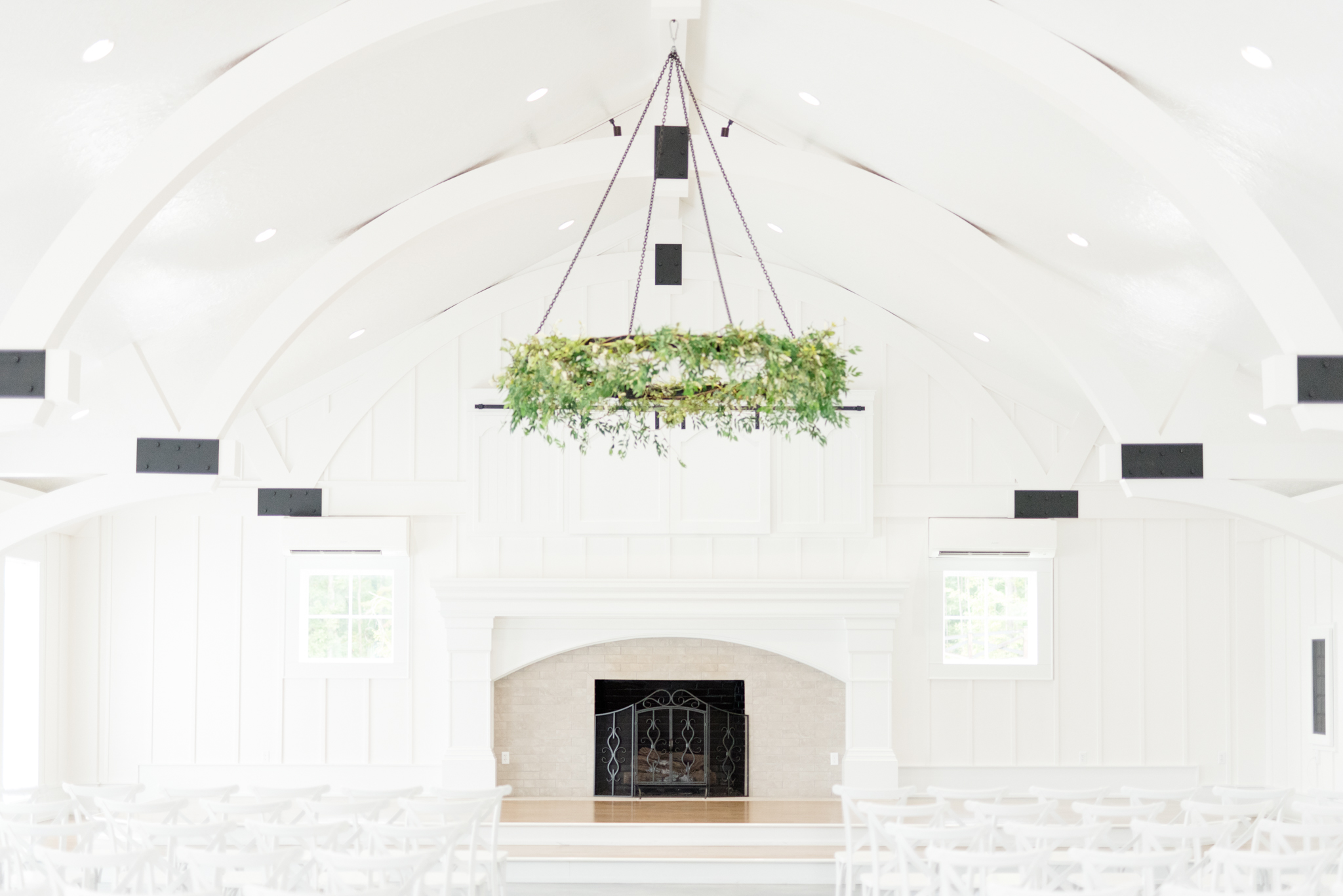 Greenery hangs above wedding ceremony stage.