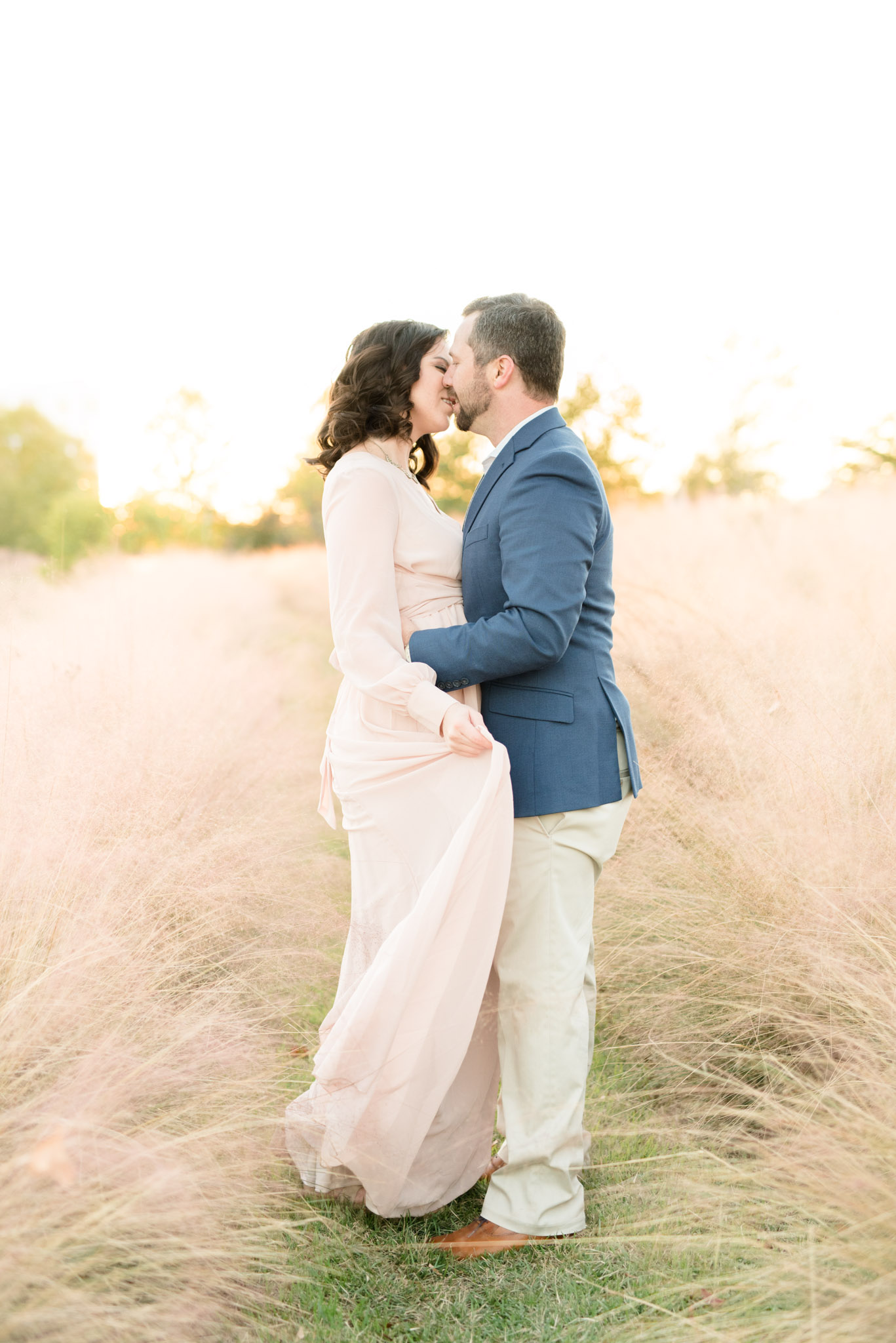 Couple kisses in field.