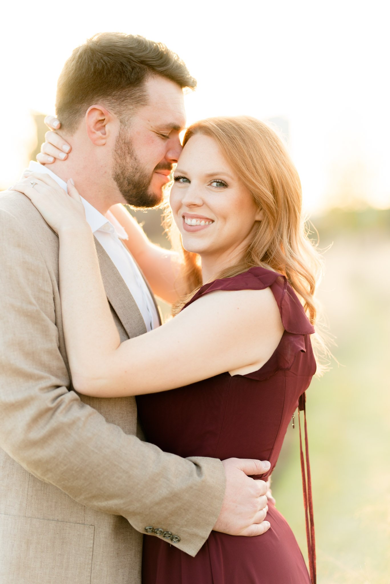 Woman smiles at camera while groom snuggles her.