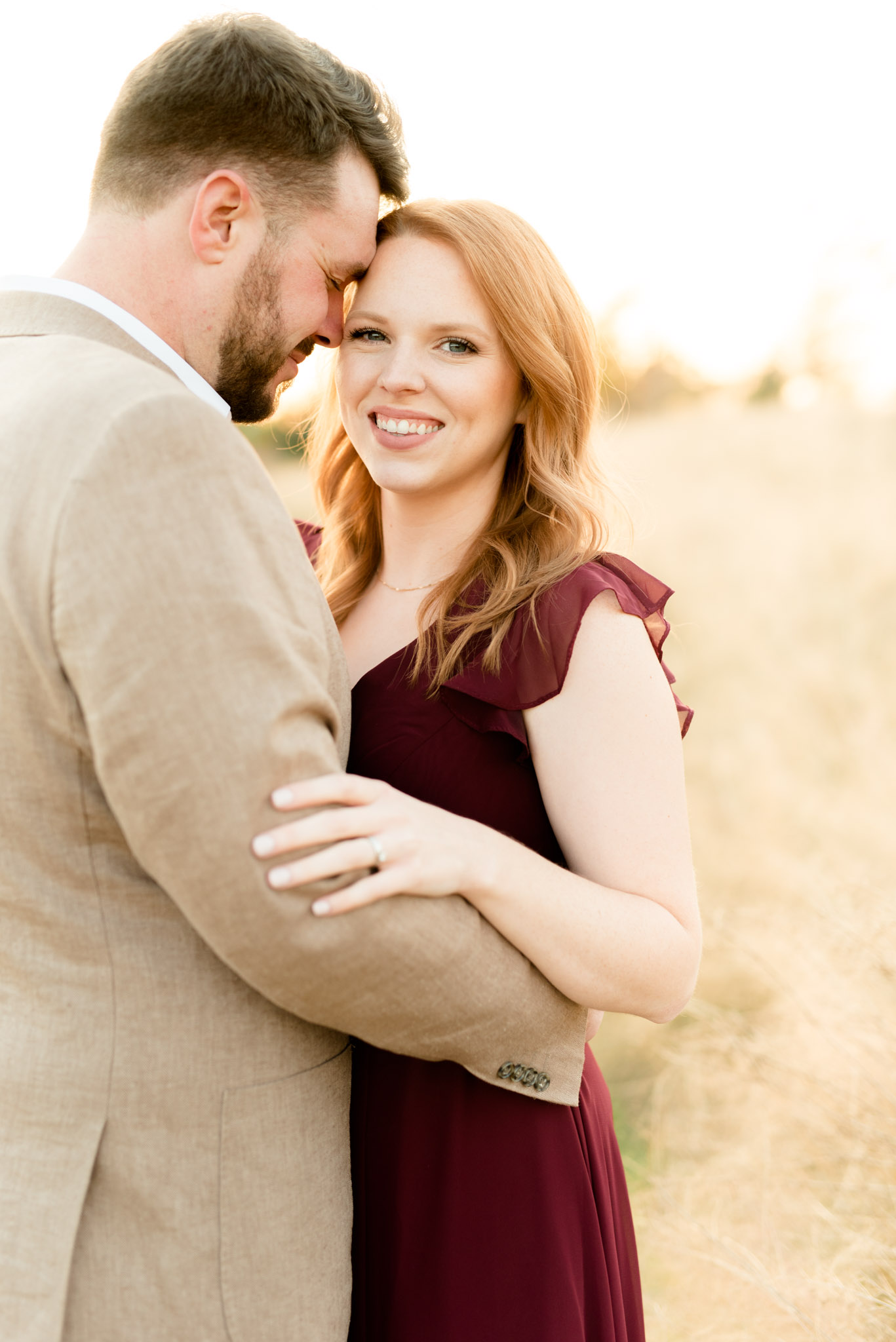 Woman smiles at camera while snuggling husband.