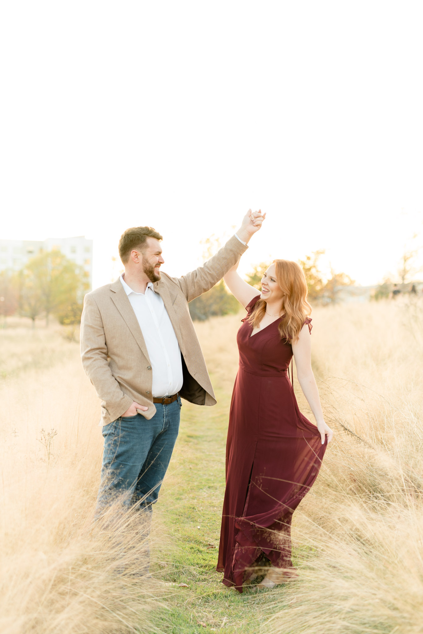 Married couple dances in sunset field.