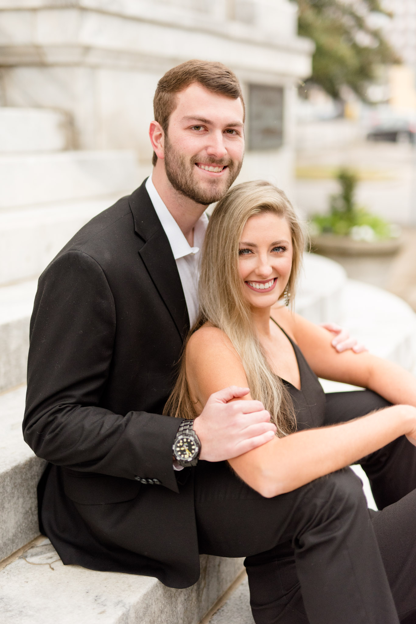 Couple sits on stairs and smiles at camera.