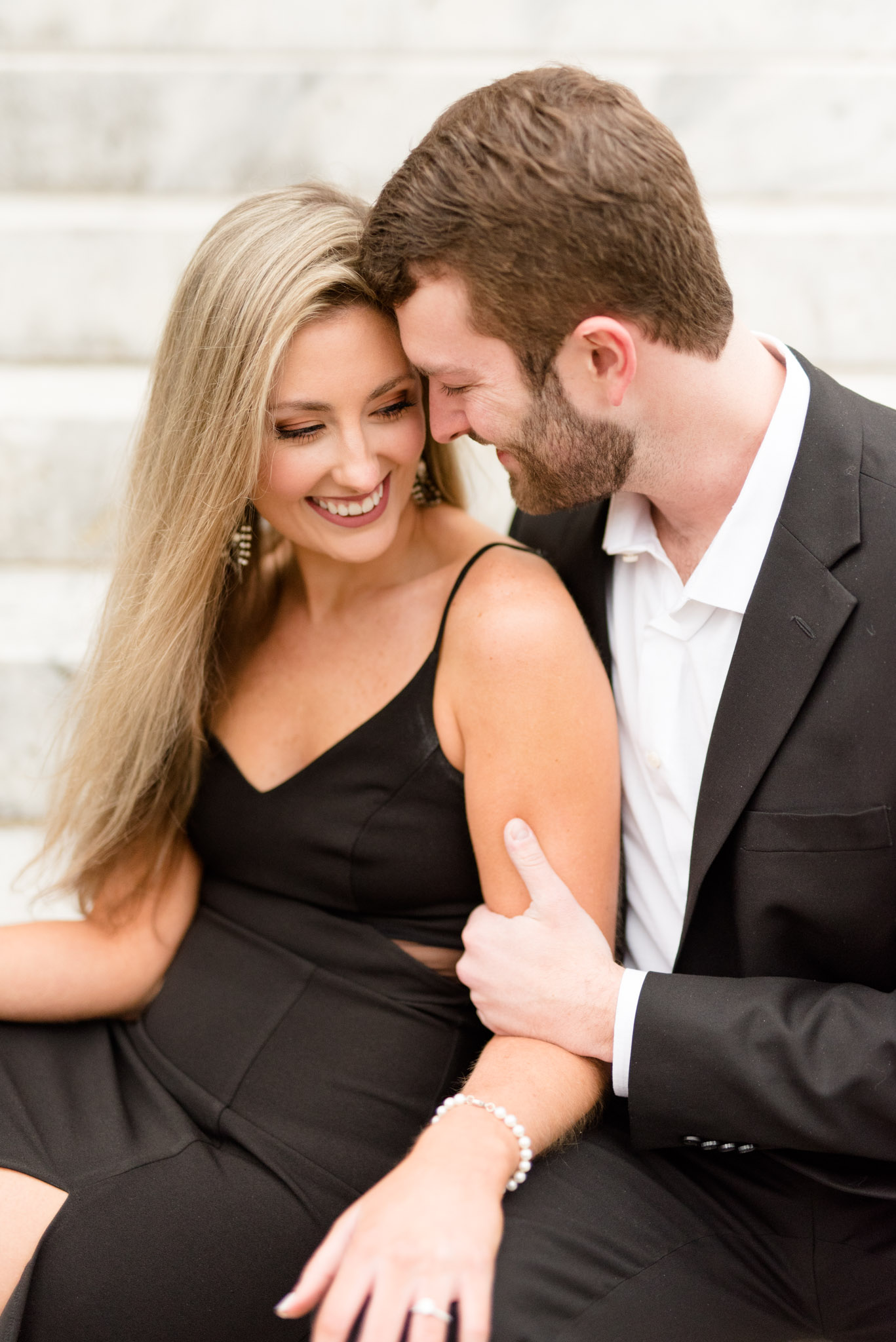 Couple laughs and snuggles on stairs.