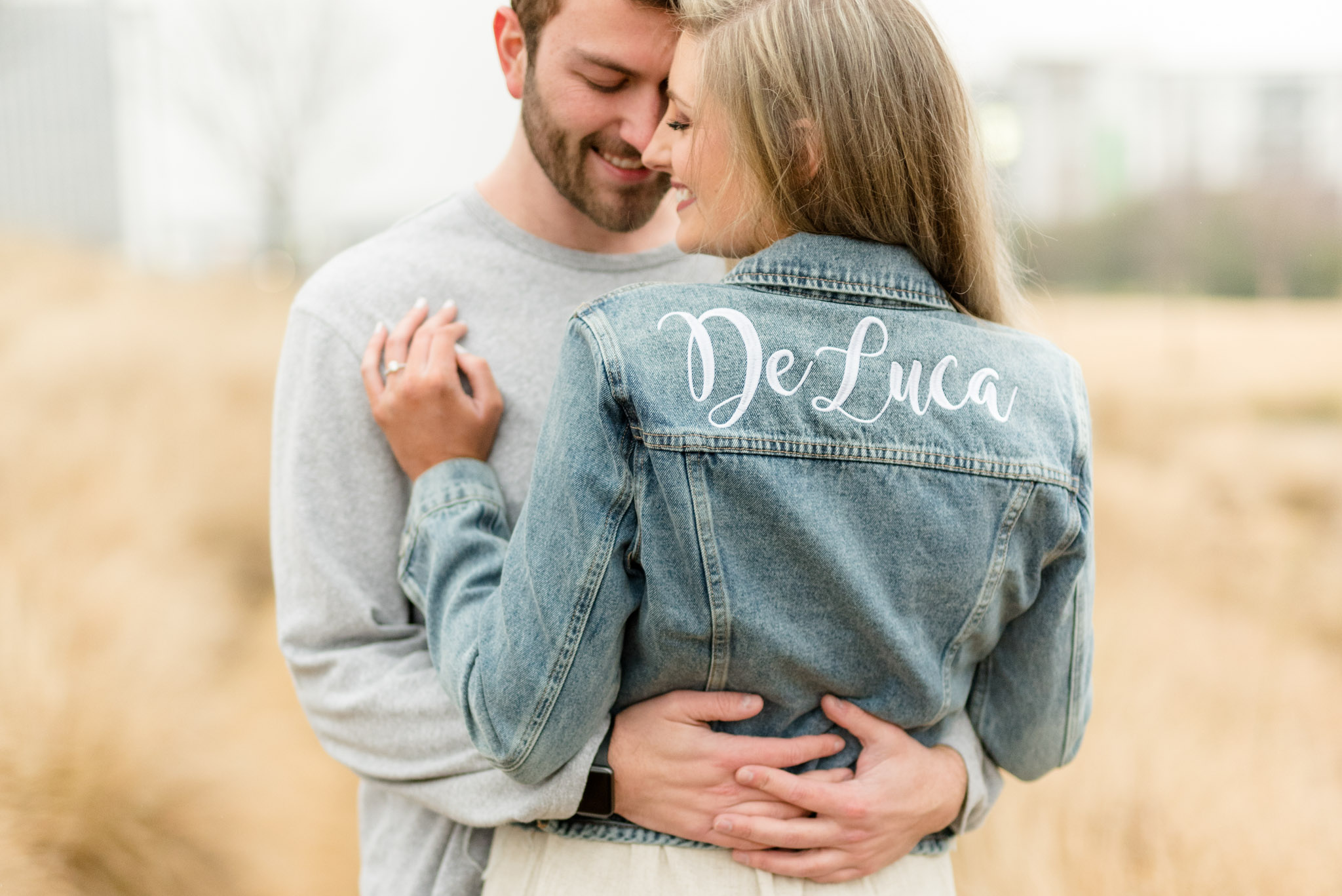 Couple cuddles showing off woman's personalized denim jacket.