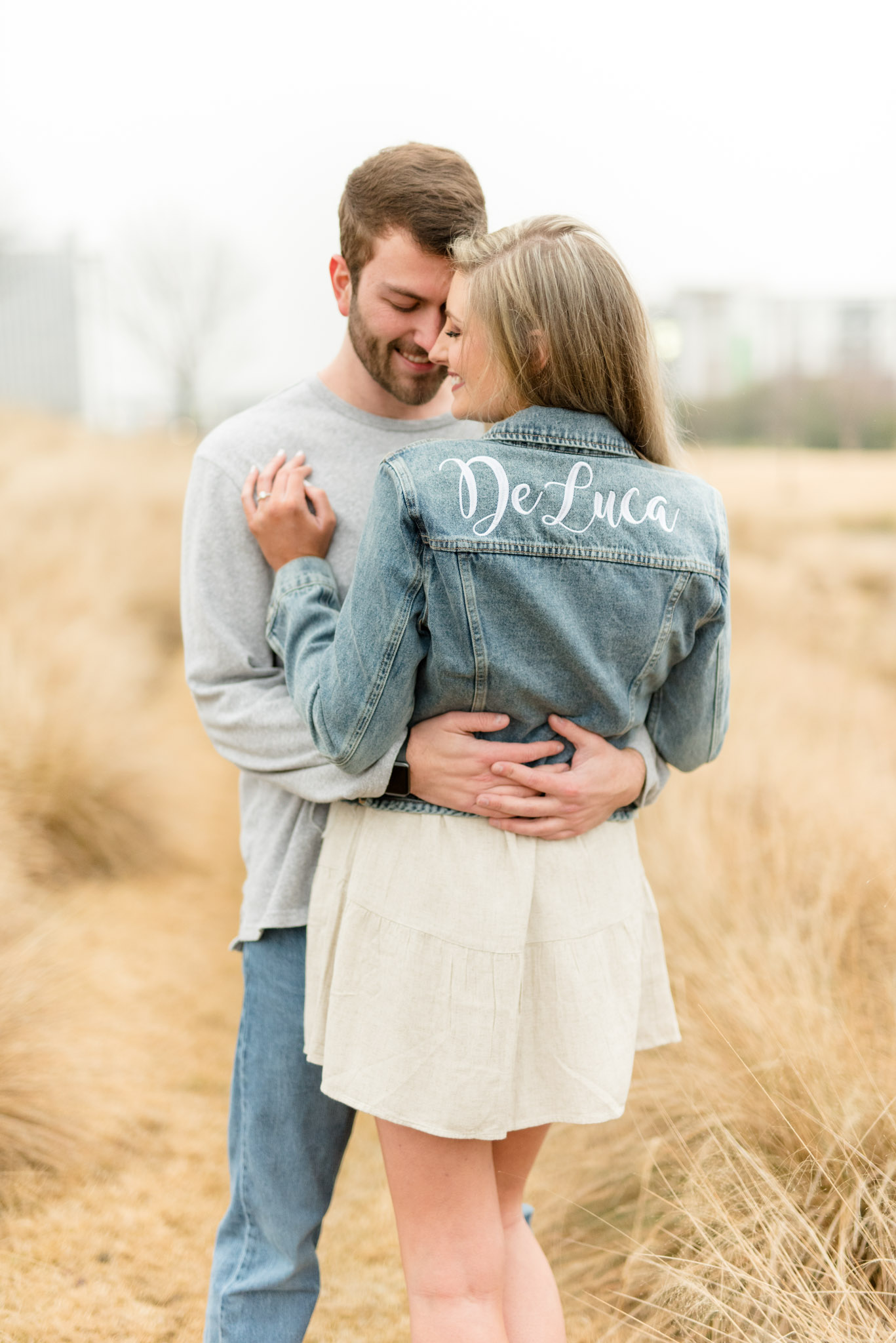 Couple hugs and woman shows off personalized jacket.