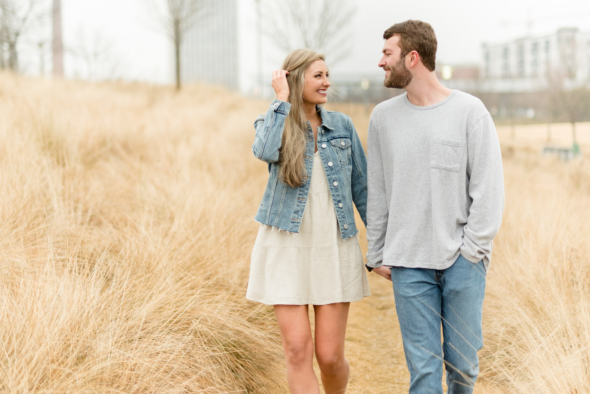 Couple walks through field and smiles.
