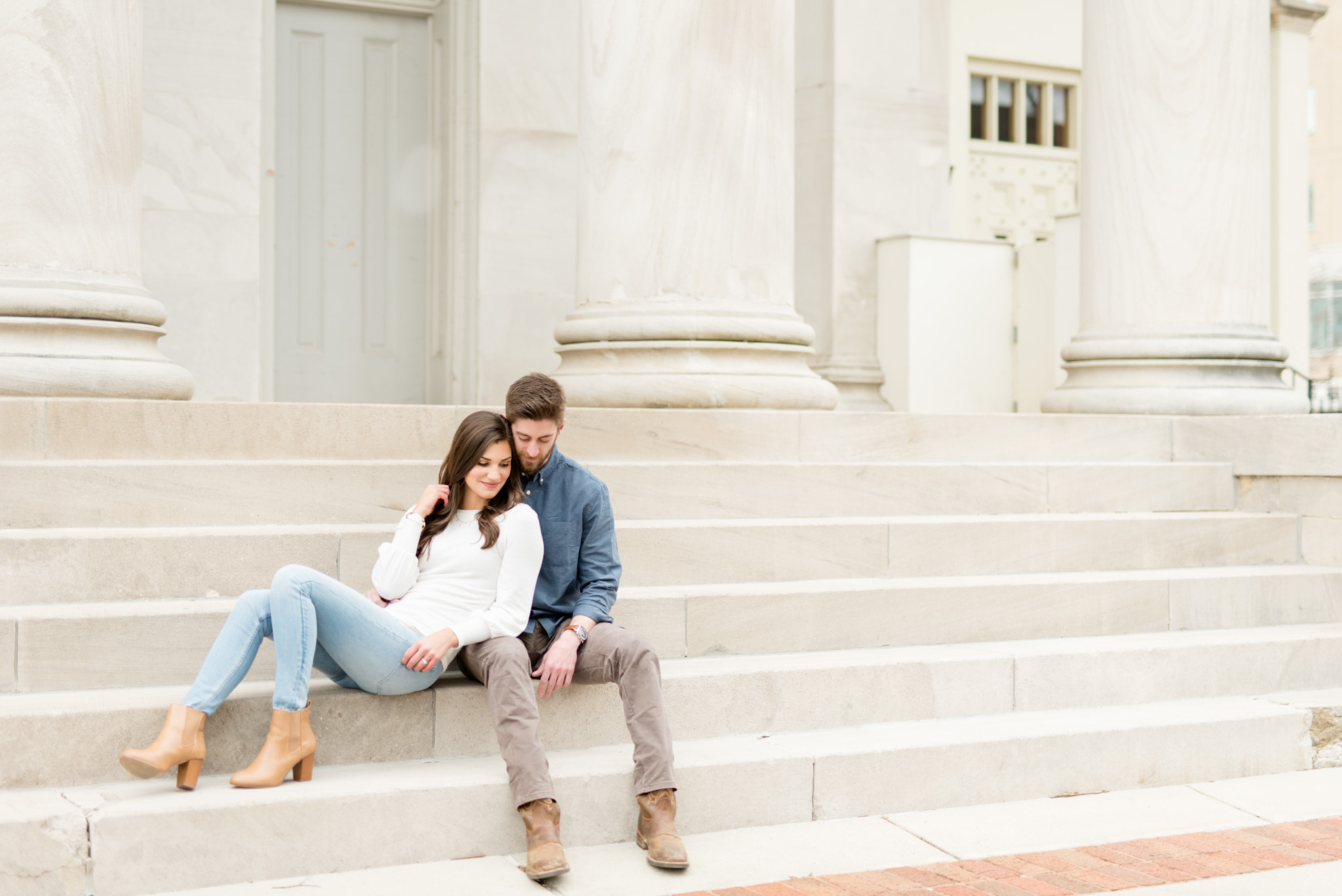 Engaged couple snuggles on stairs.