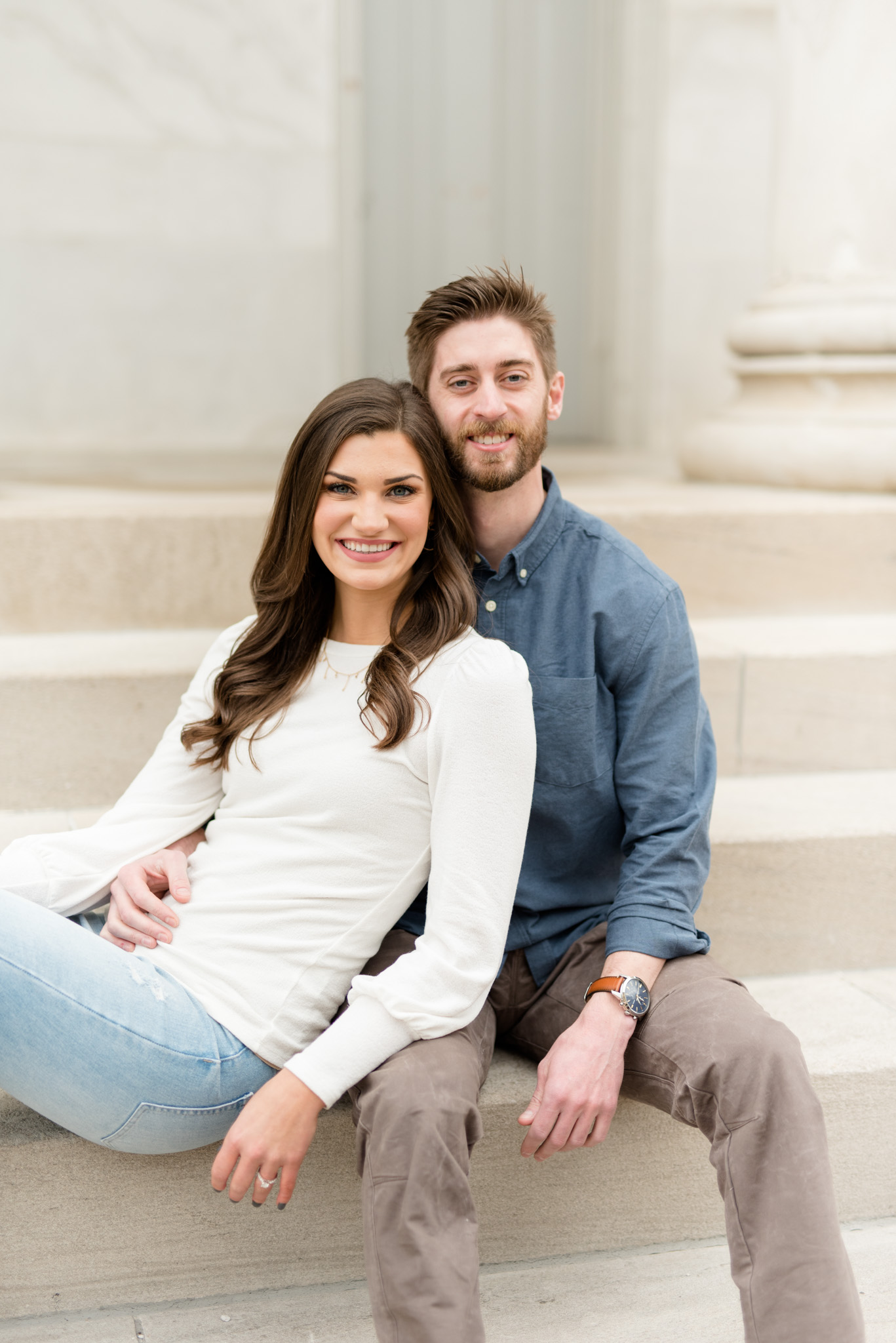 Couple sit on stairs and smile at camera.