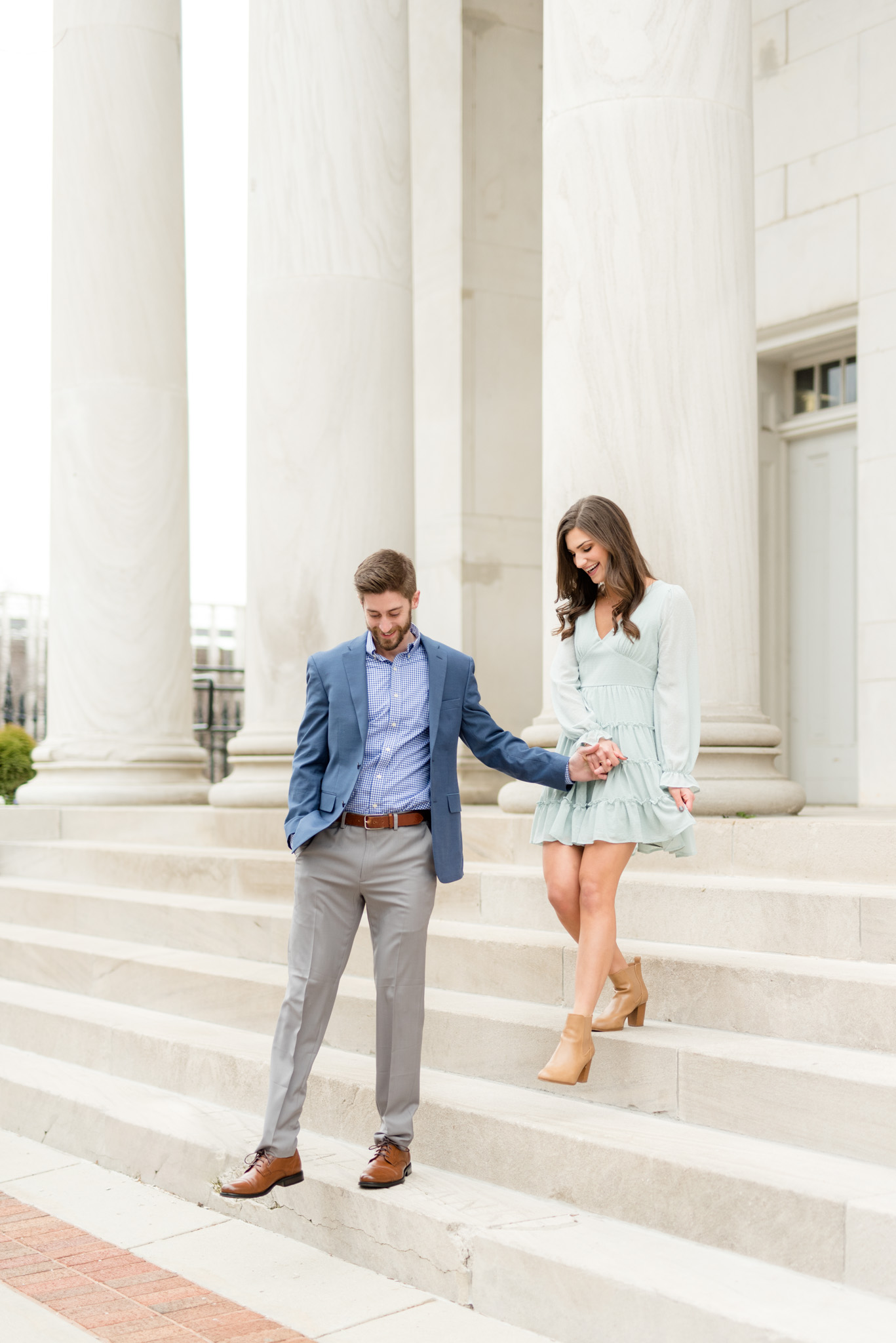 Couple walks down marble staircase.