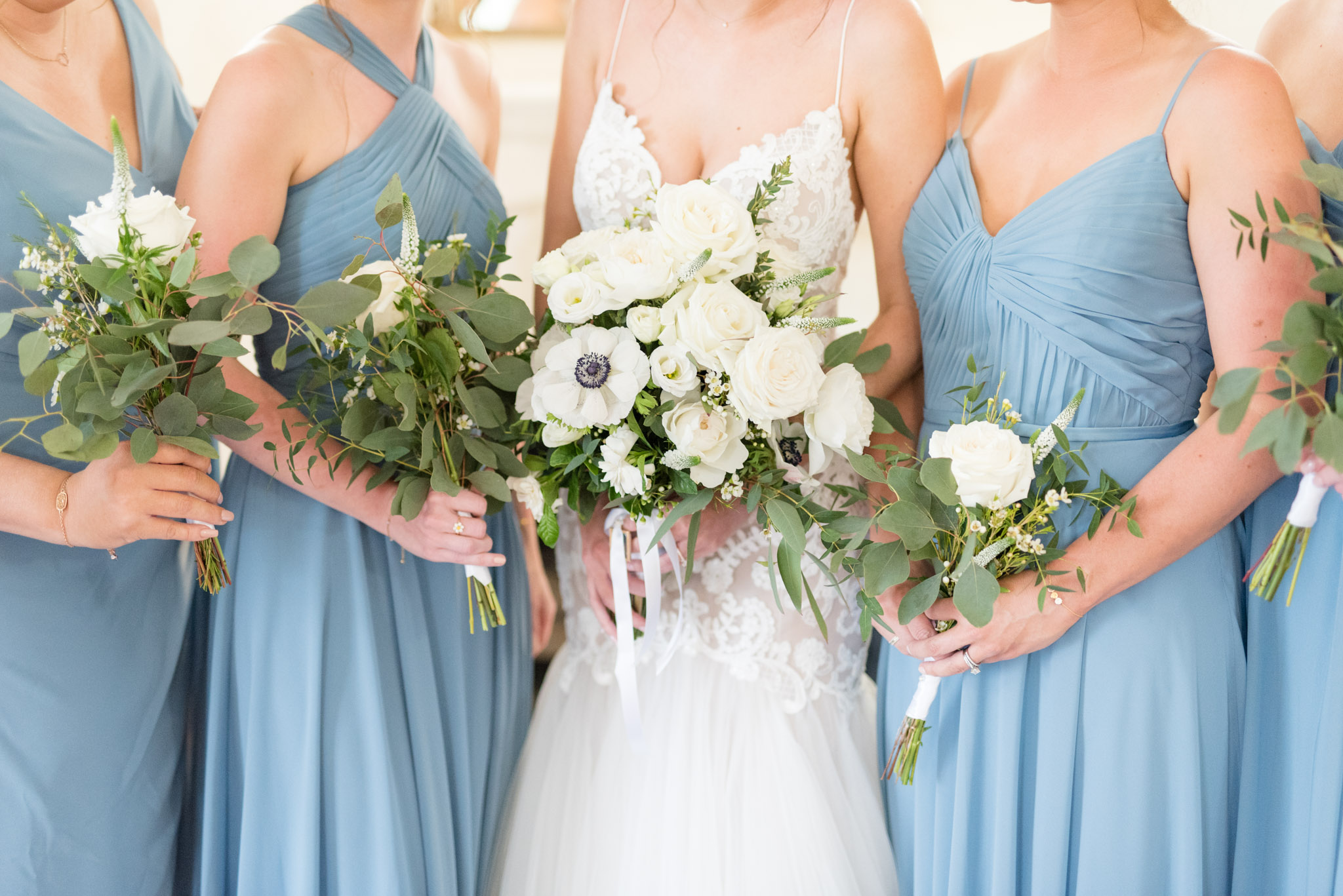 Bride and bridesmaids hold white bouquets.