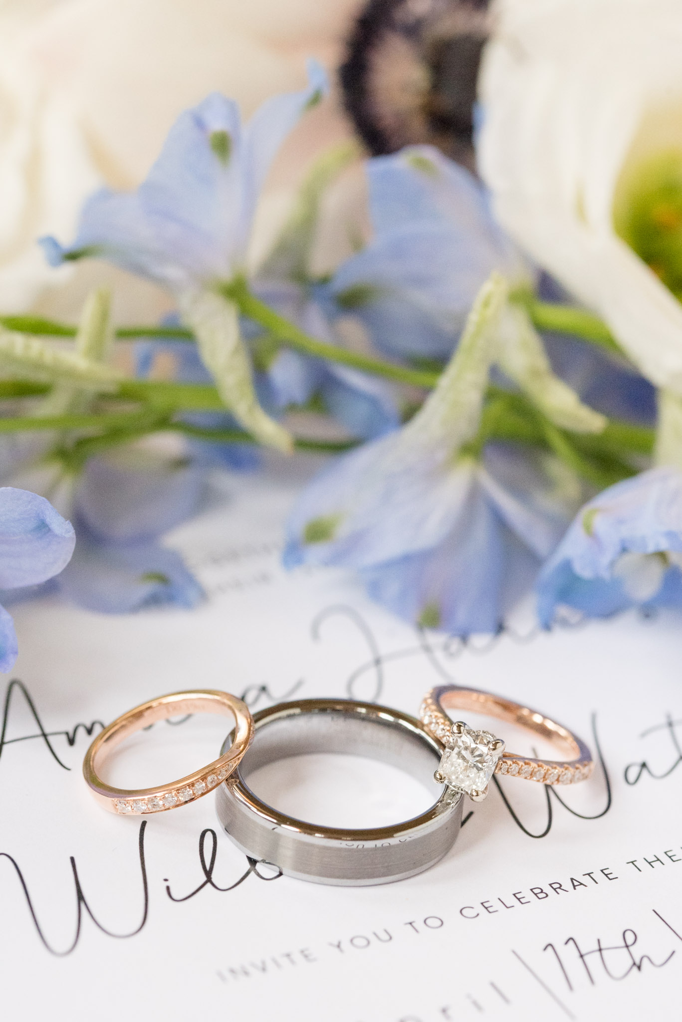 Wedding rings sit on invitation.