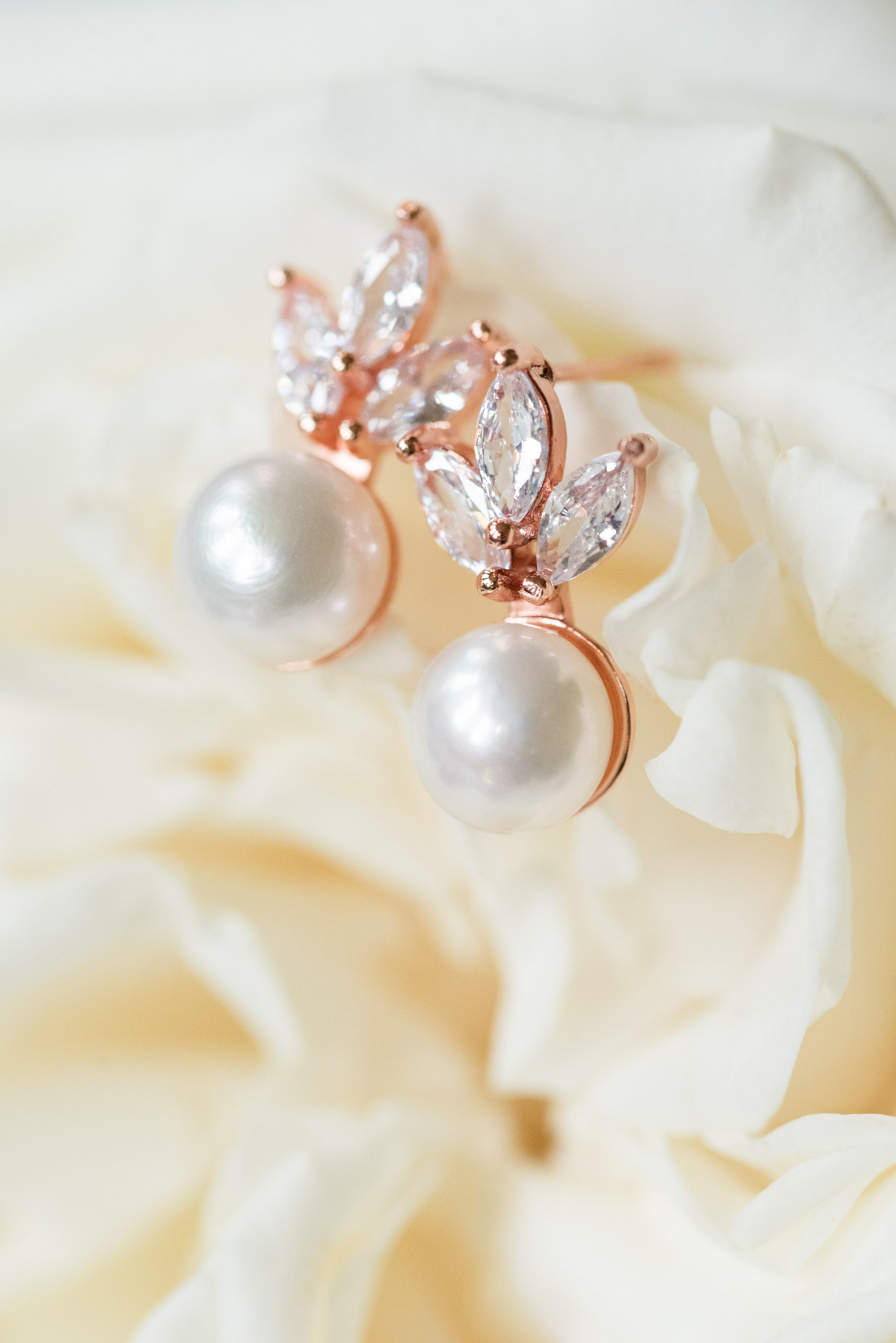 Bride's earrings sit on flower.