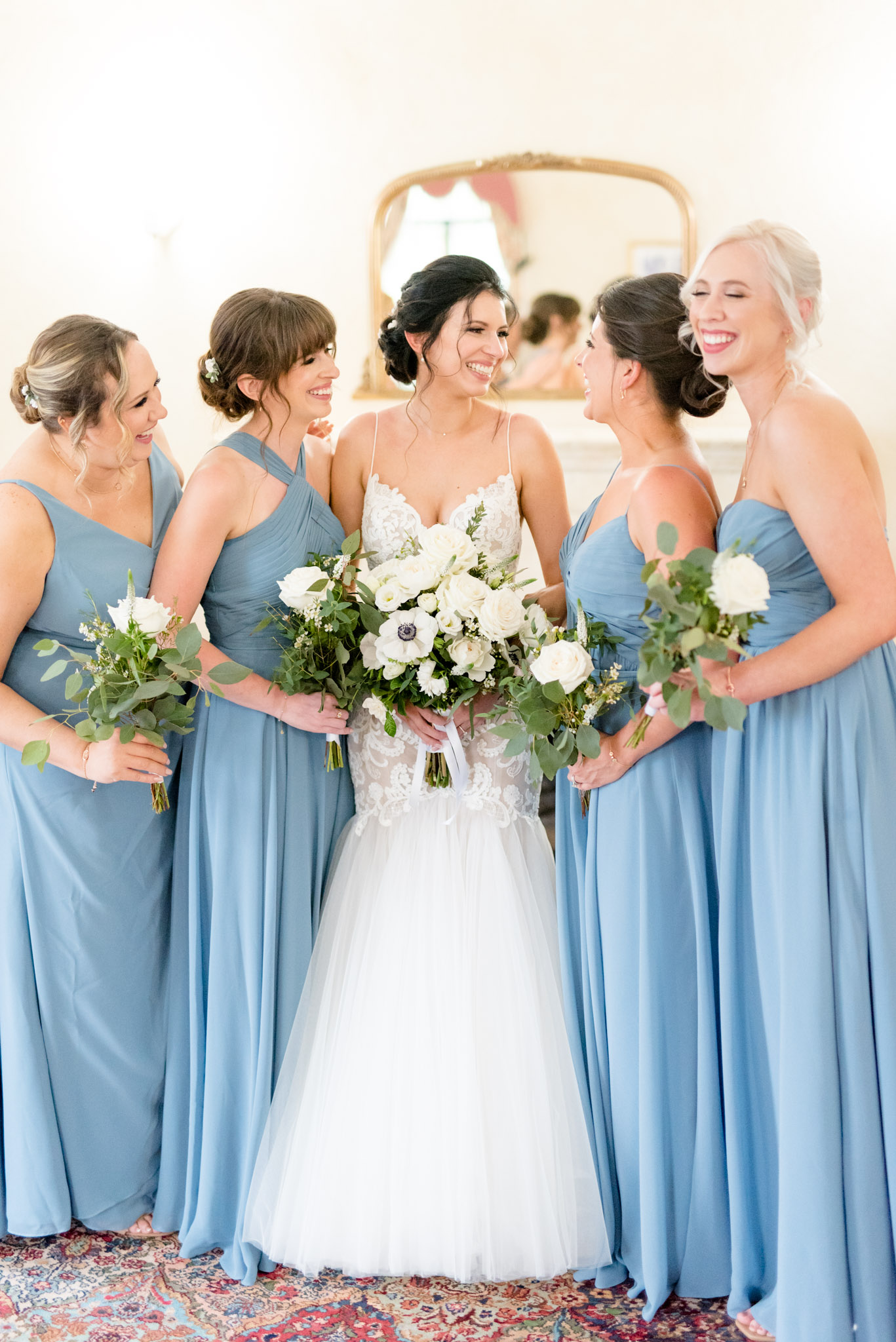 Bride and bridesmaids smile at each other.