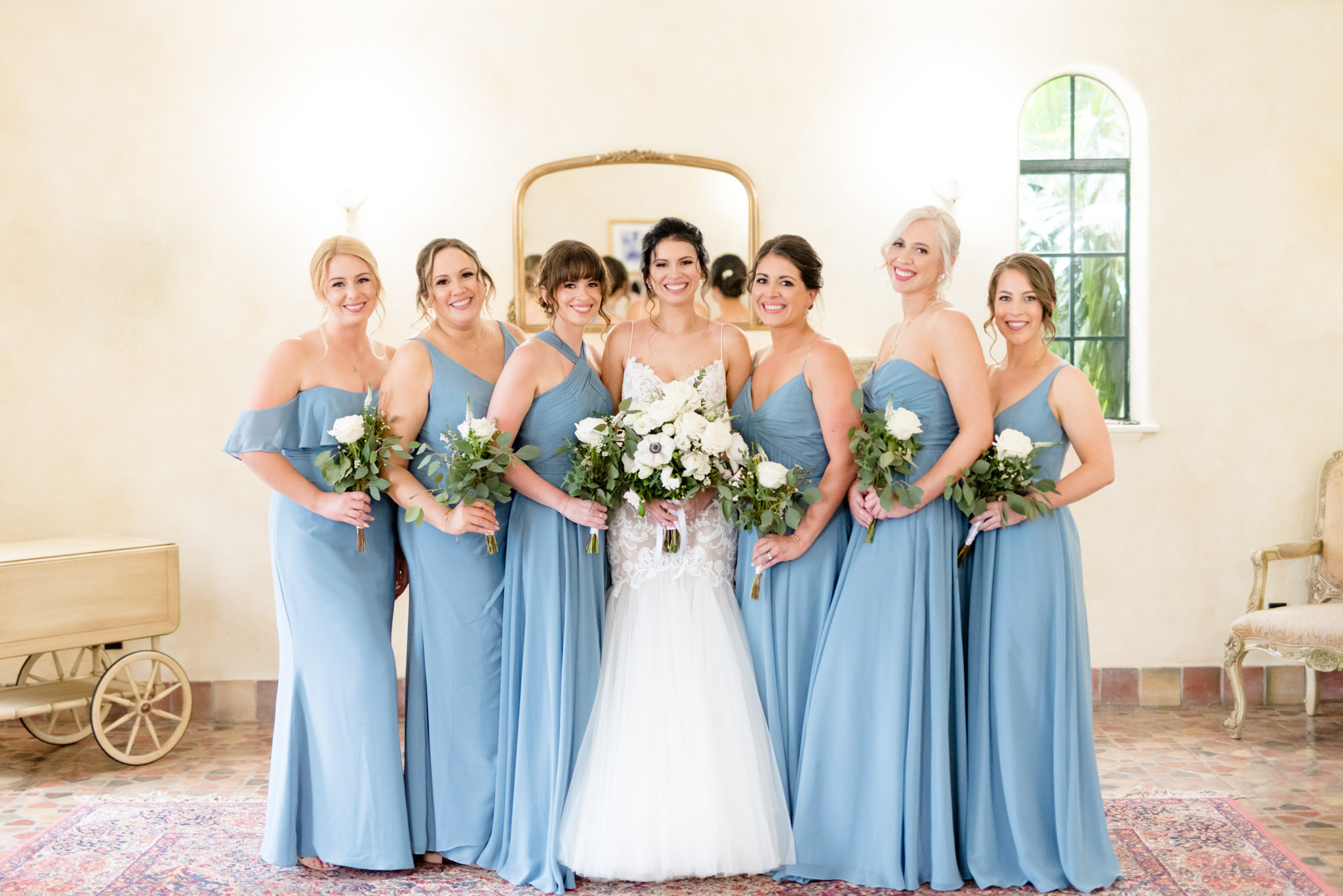 Bride and bridesmaids smile and hold bouquets.