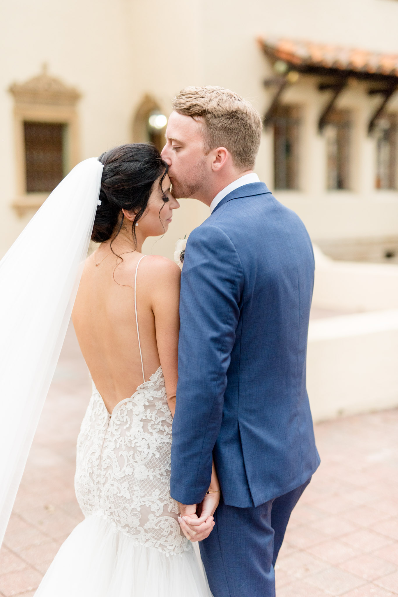 Groom kisses bride's forehead.