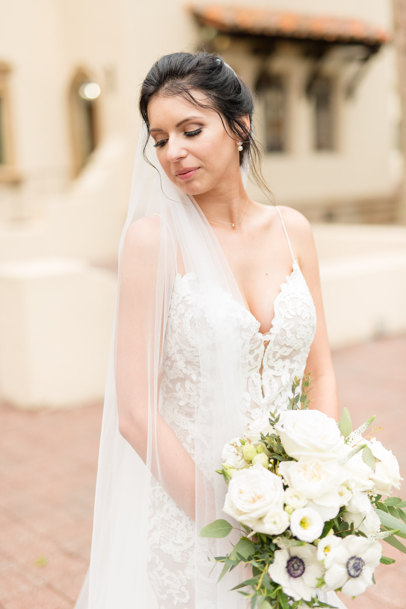 Bride looks over shoulder while holding flowers.