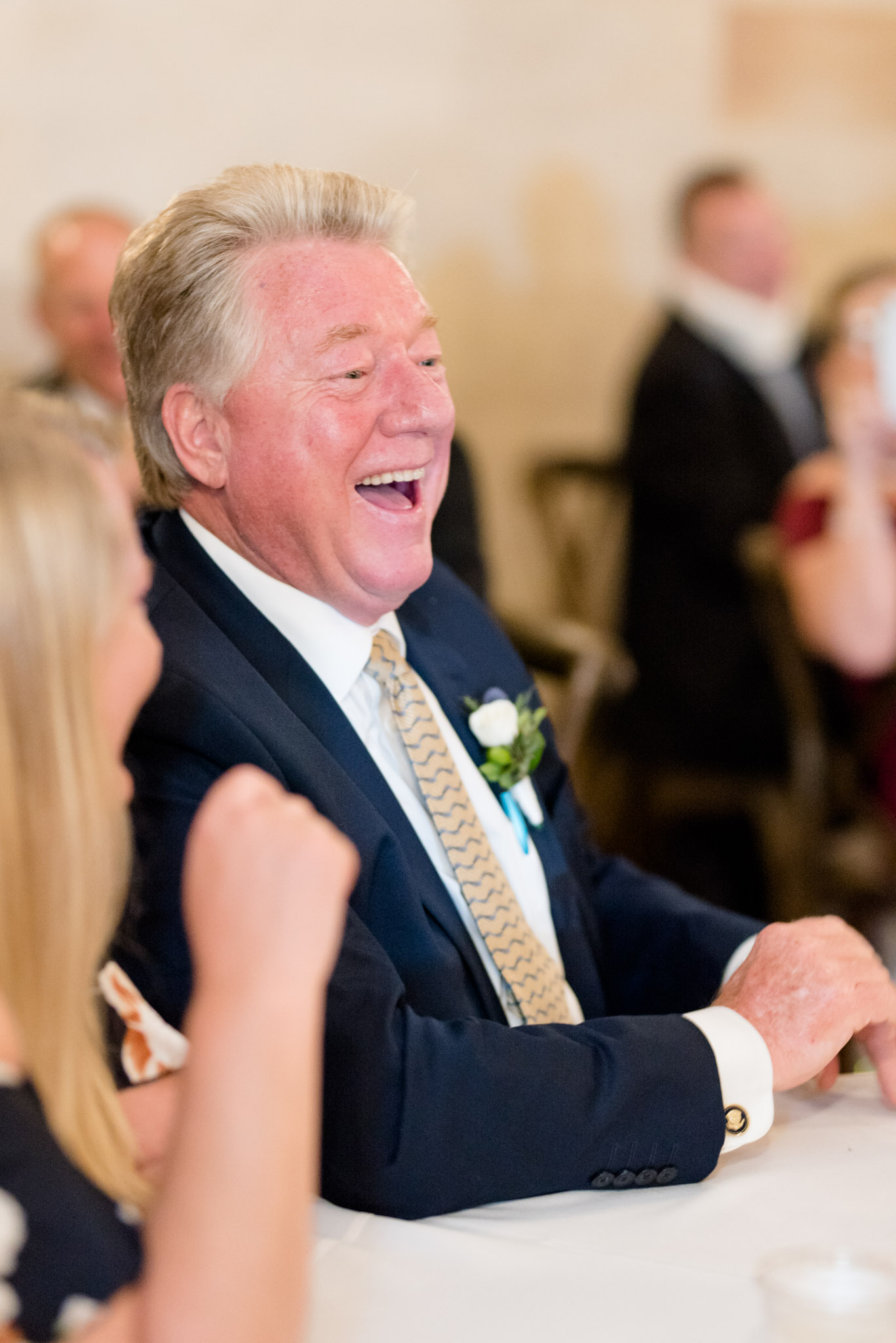Father of the groom laughs during reception.