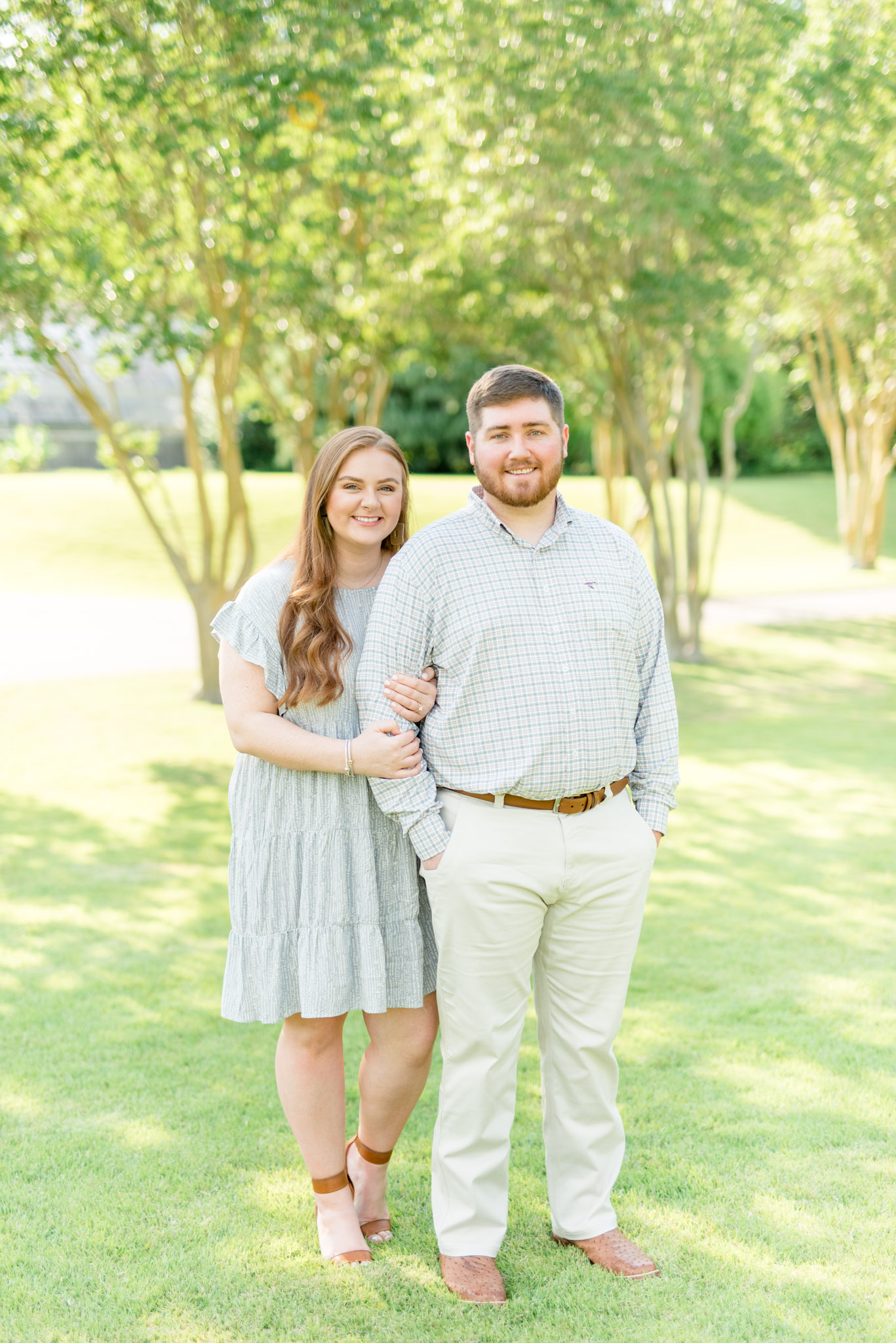 Couple smiles in grassy field.