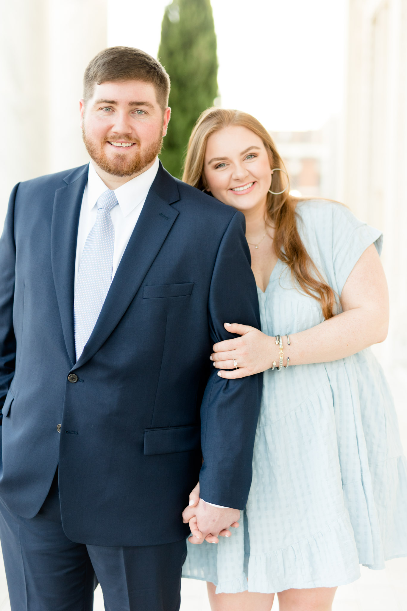 Couple smiles at camera and cuddles.