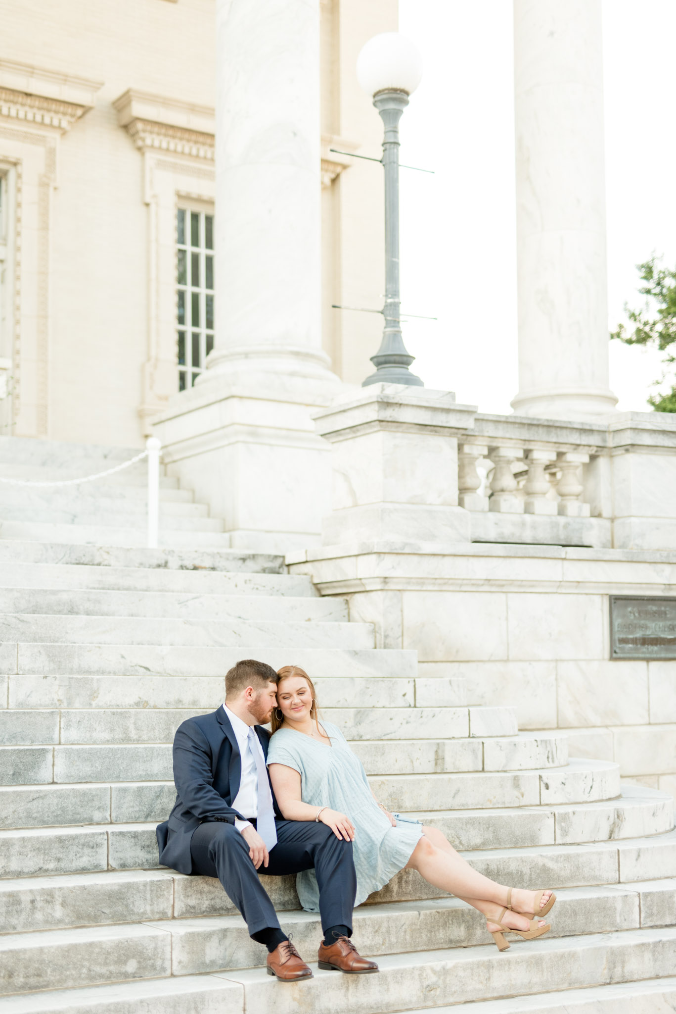 Couple cuddles on marble stairsteps.