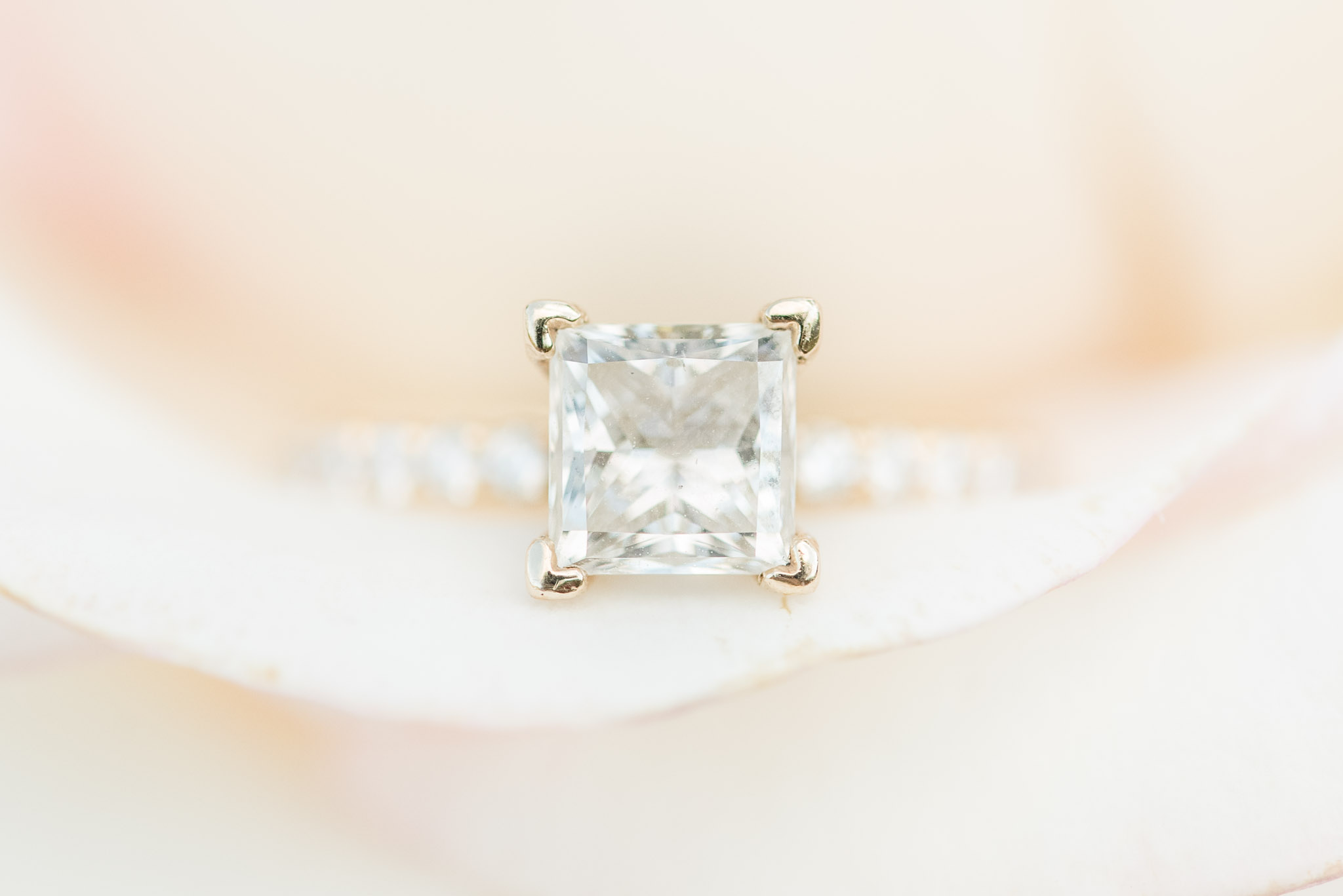 Square diamond ring sits in flower.