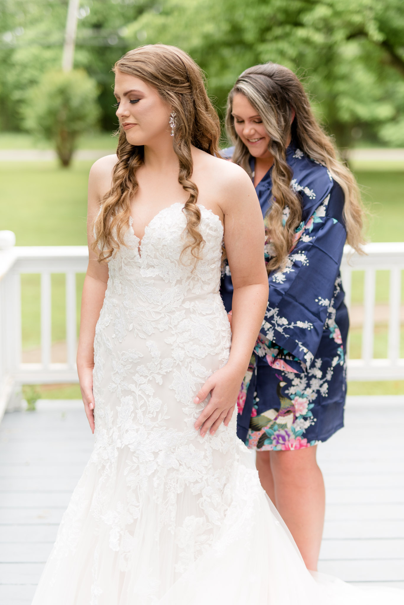 Bridesmaid buttons up bride's dress.