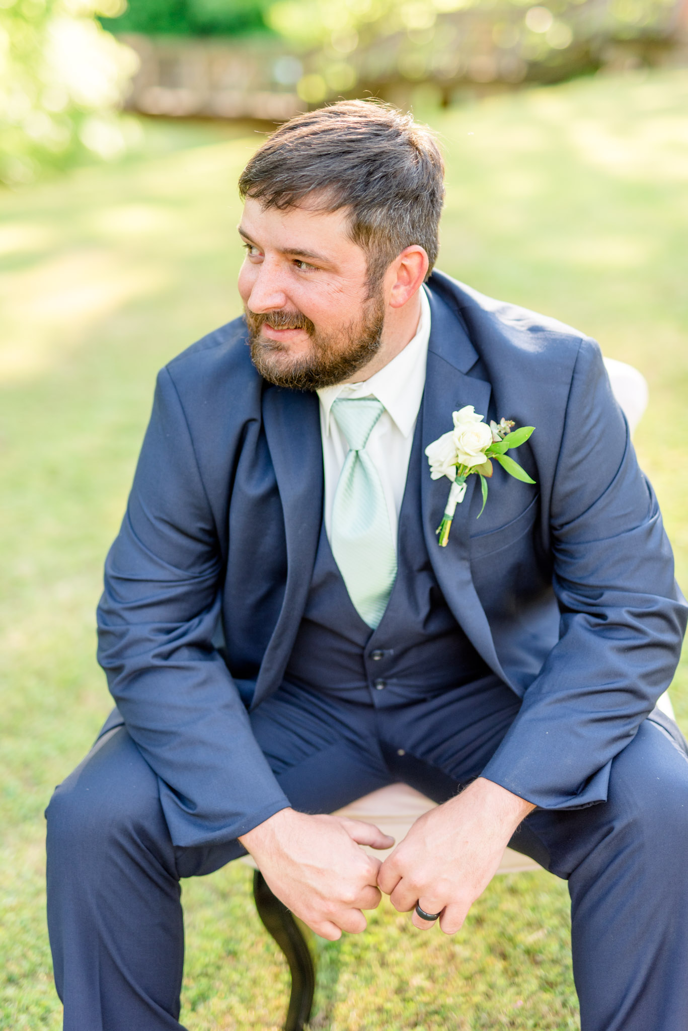 Groom looks over shoulder while sitting.