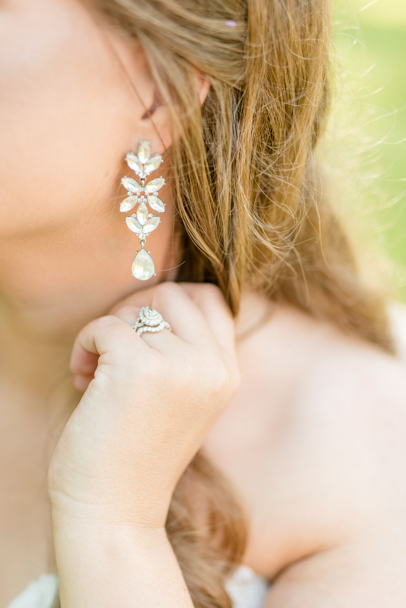 Bride shows off ring and earrings.