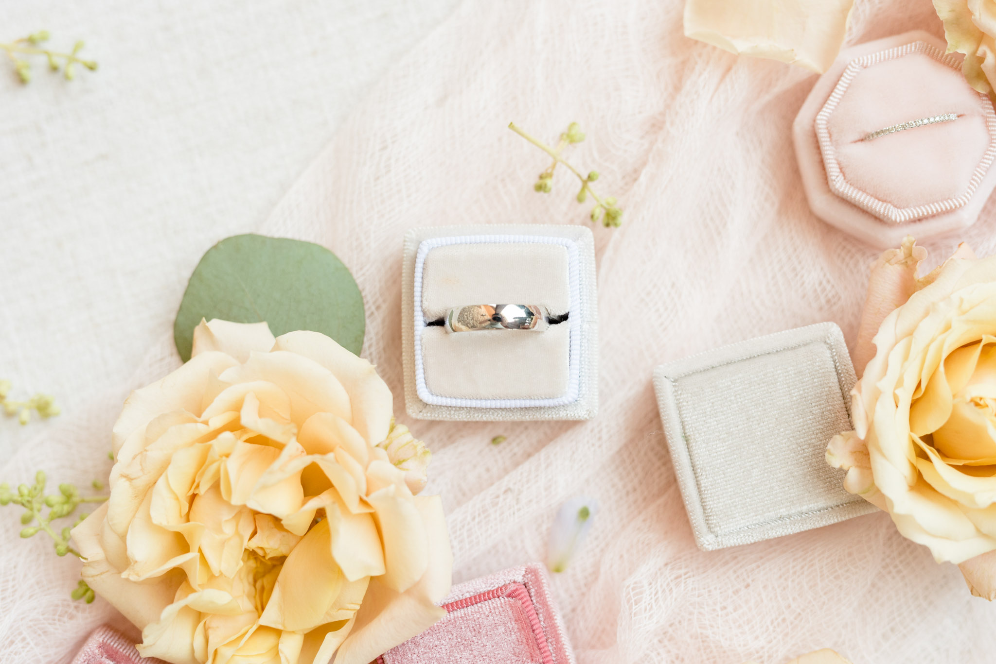 Groom's wedding ring sits in cream box.