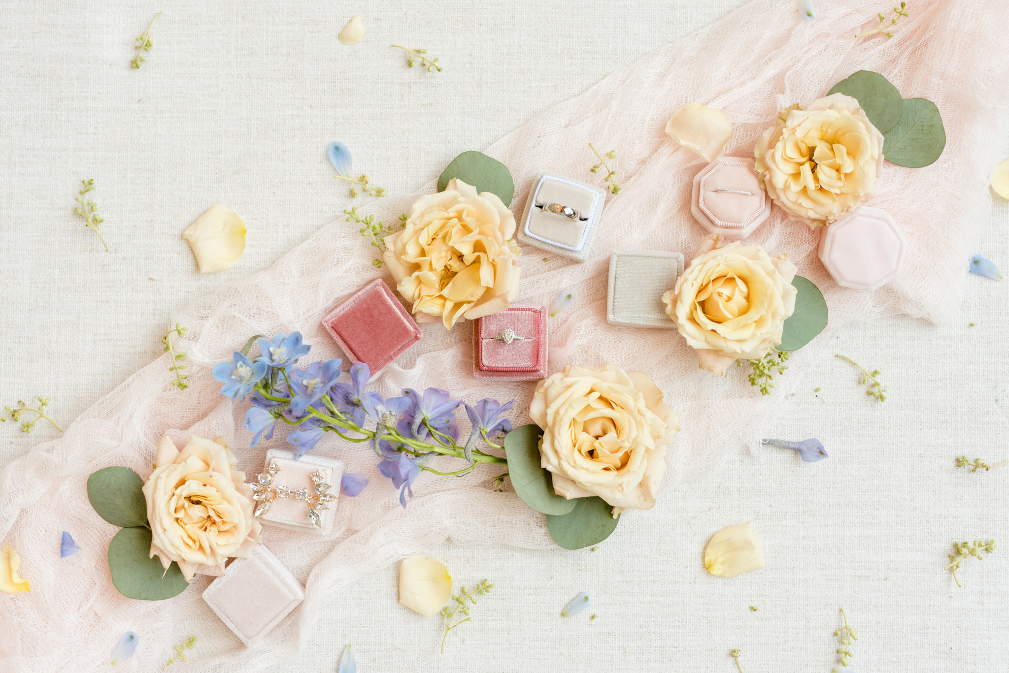 Wedding jewelry sits with flowers and ribbon.