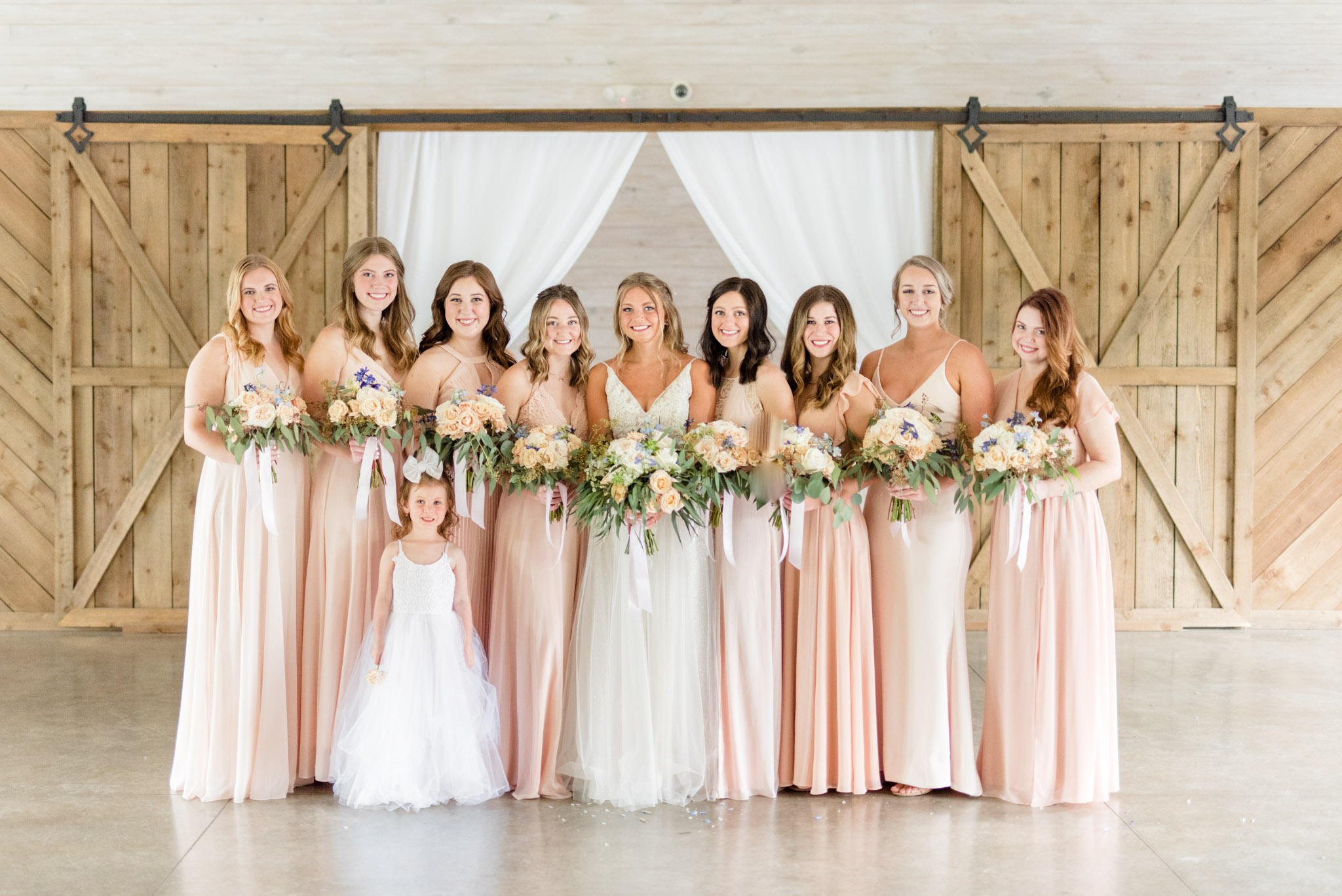Bride and bridesmaids smile in hall.