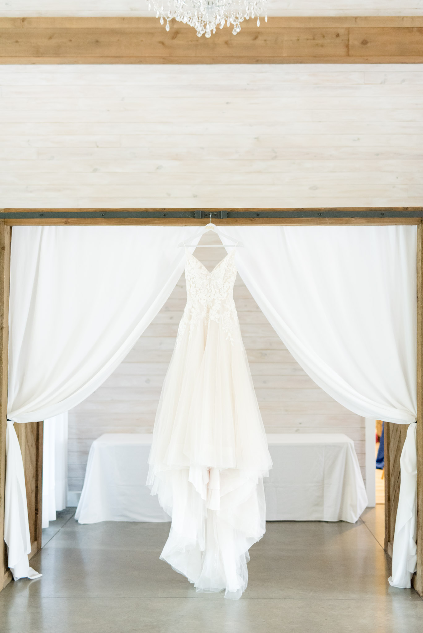 Bridal gown hangs on beam.