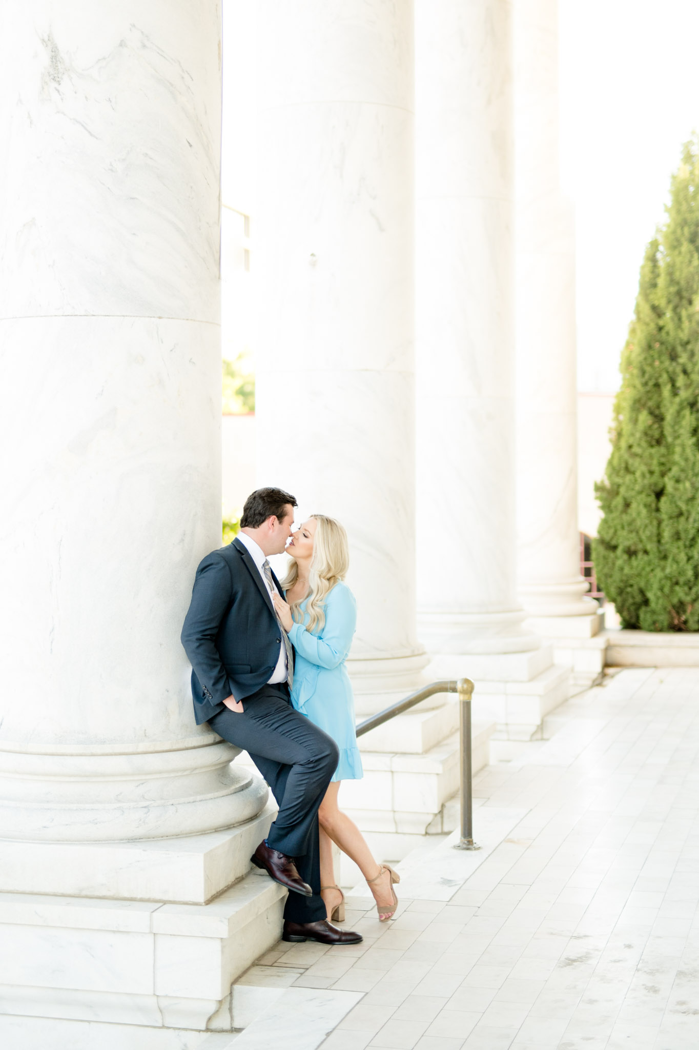 Man and woman lean up against marble column. 