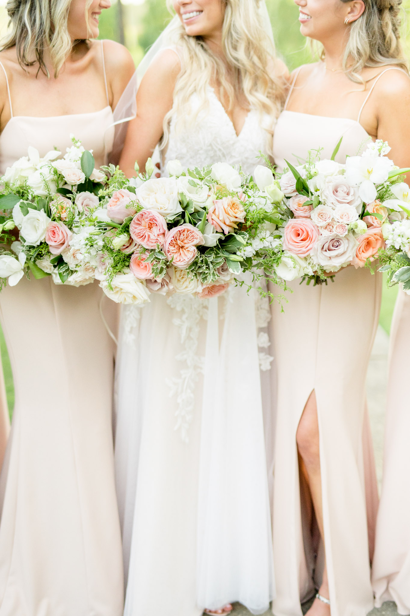 Bride and bridesmaids hold pink and white flowers.