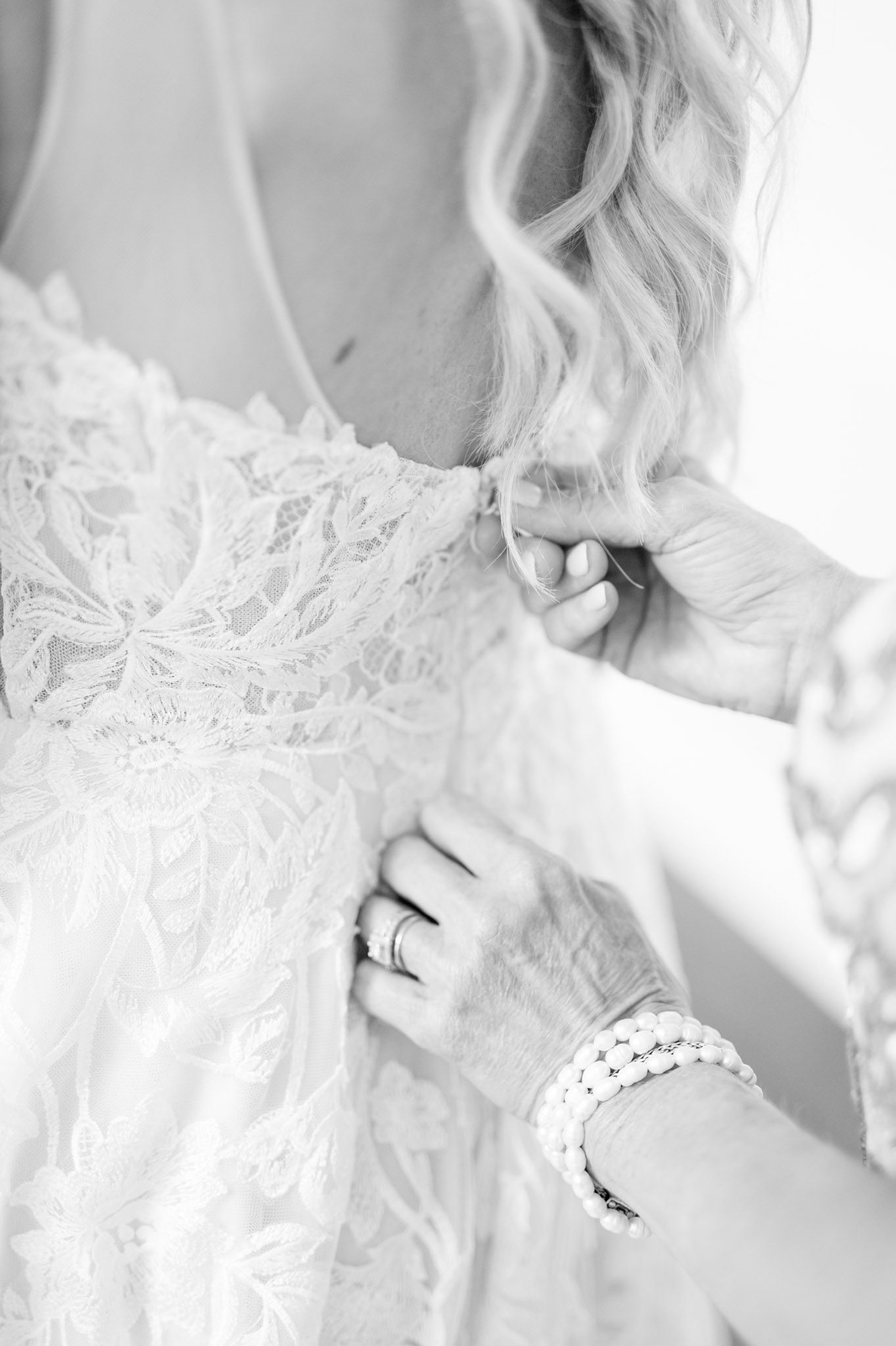 Mother of bride zips up wedding gown.