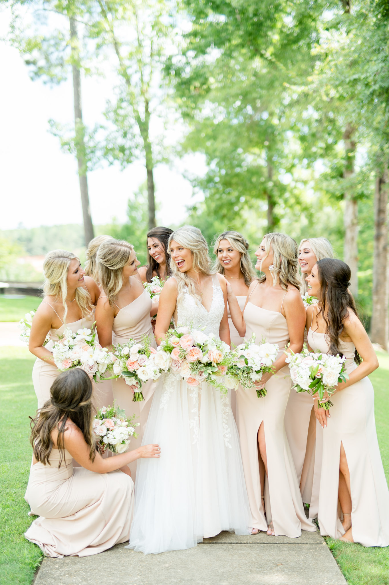 Bride laughs while bridesmaids help her get ready.