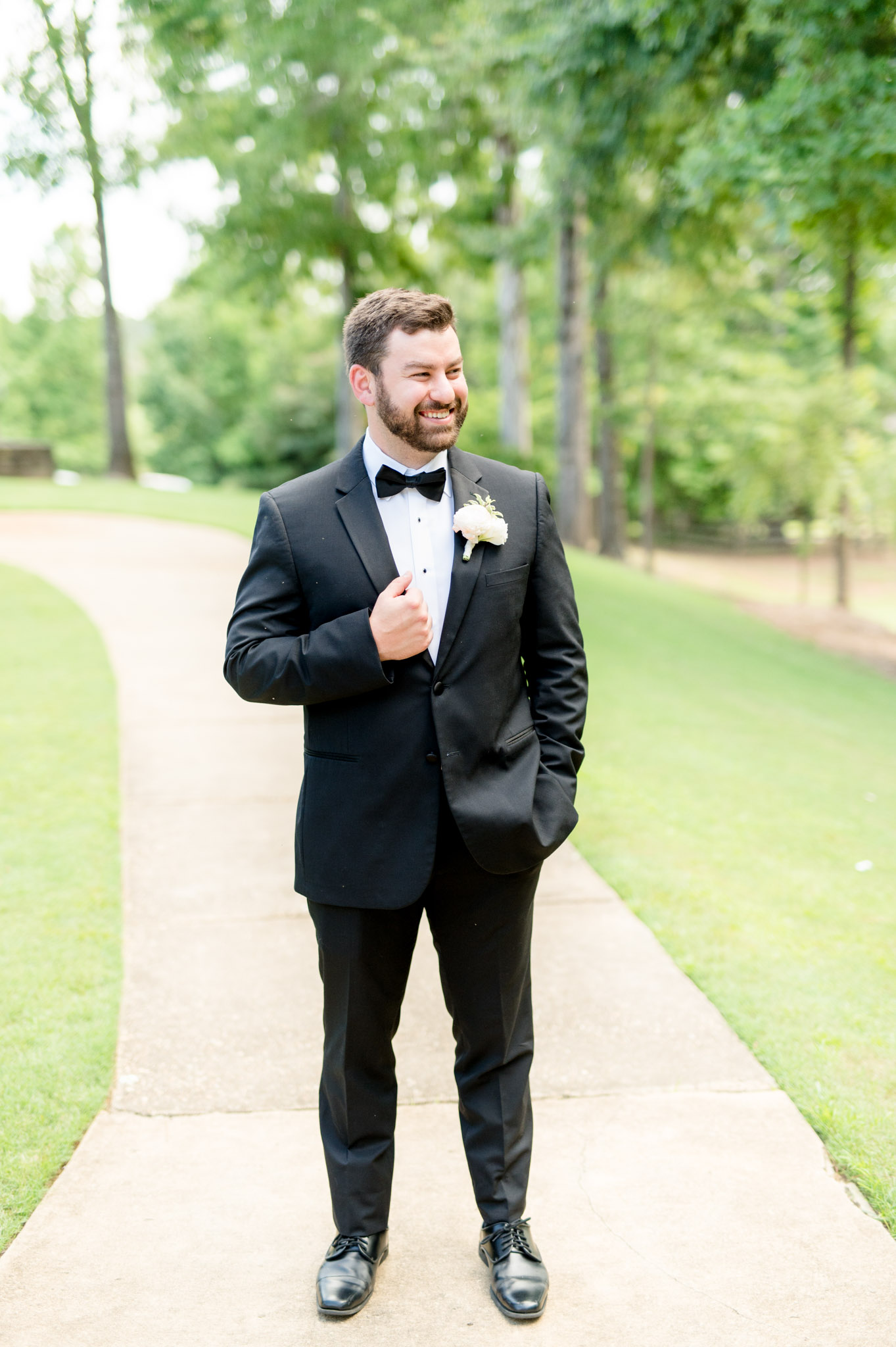 Groom holds lapel and looks off to side.