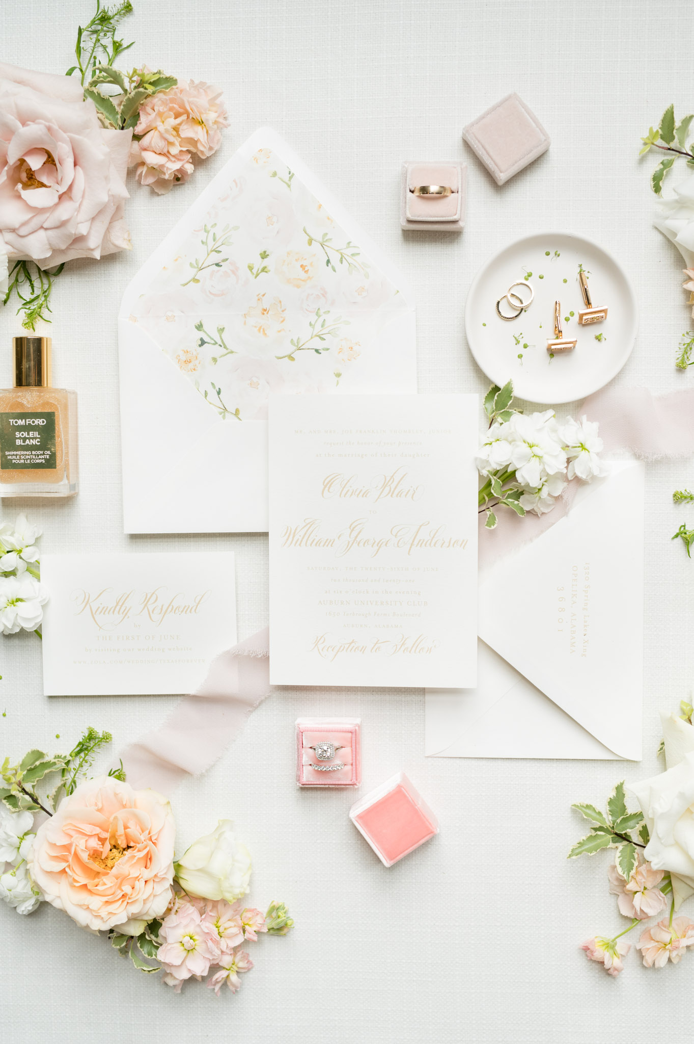 Multi-piece invitation suite sits with flowers and details.