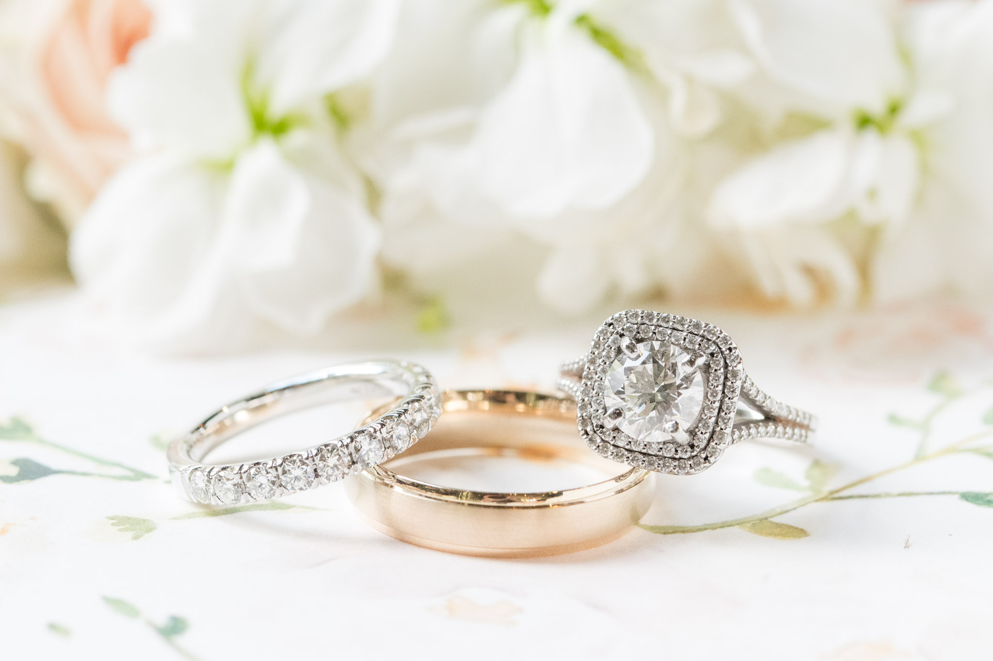 Wedding rings sit in front of flowers.